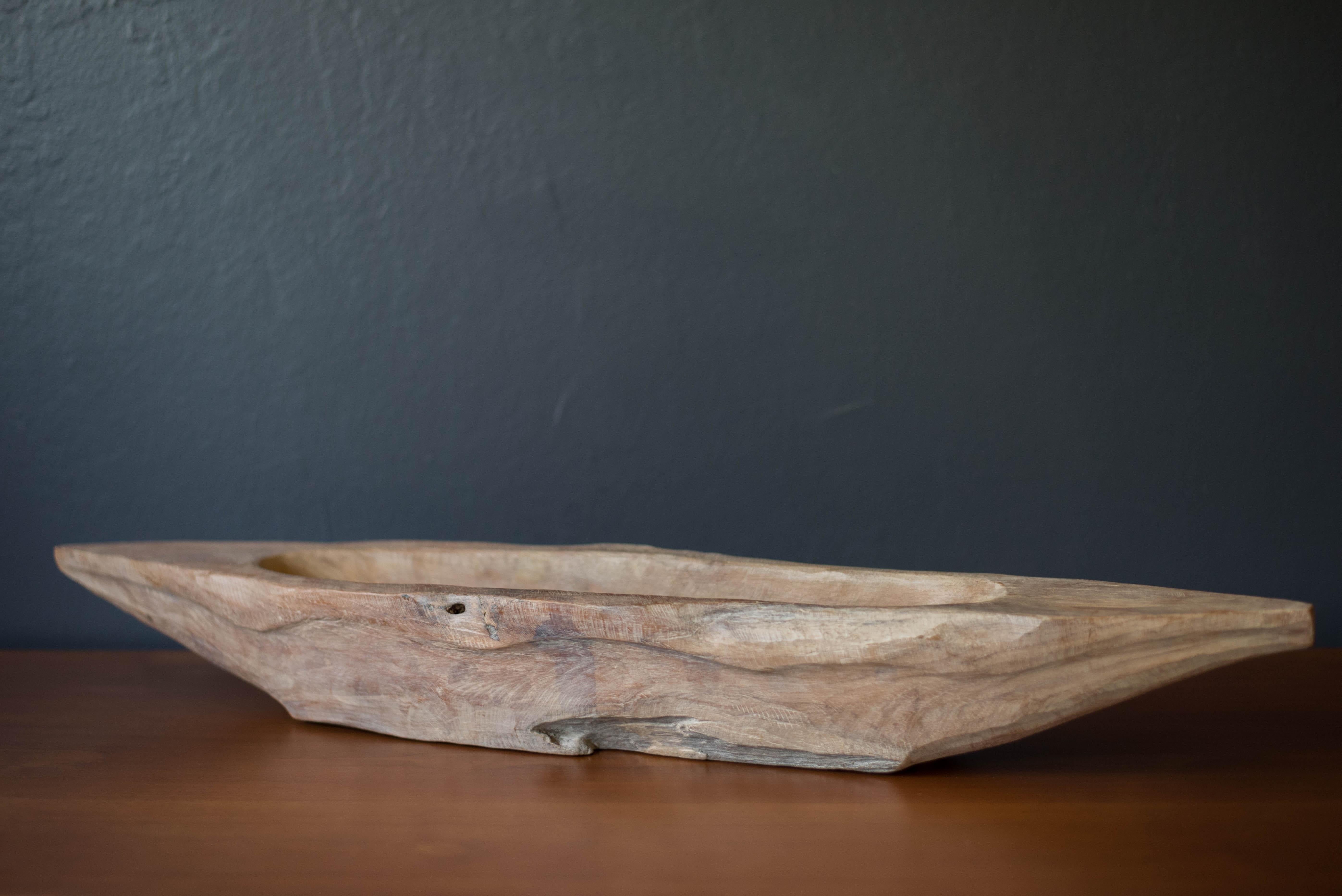 Vintage sculptural decorative centerpiece serving bowl circa 1970s. Crafted in a hand carved canoe shape that has been naturally aged displaying plenty of rustic charm and patina. The perfect home decor piece that can be accessorized with fruit,