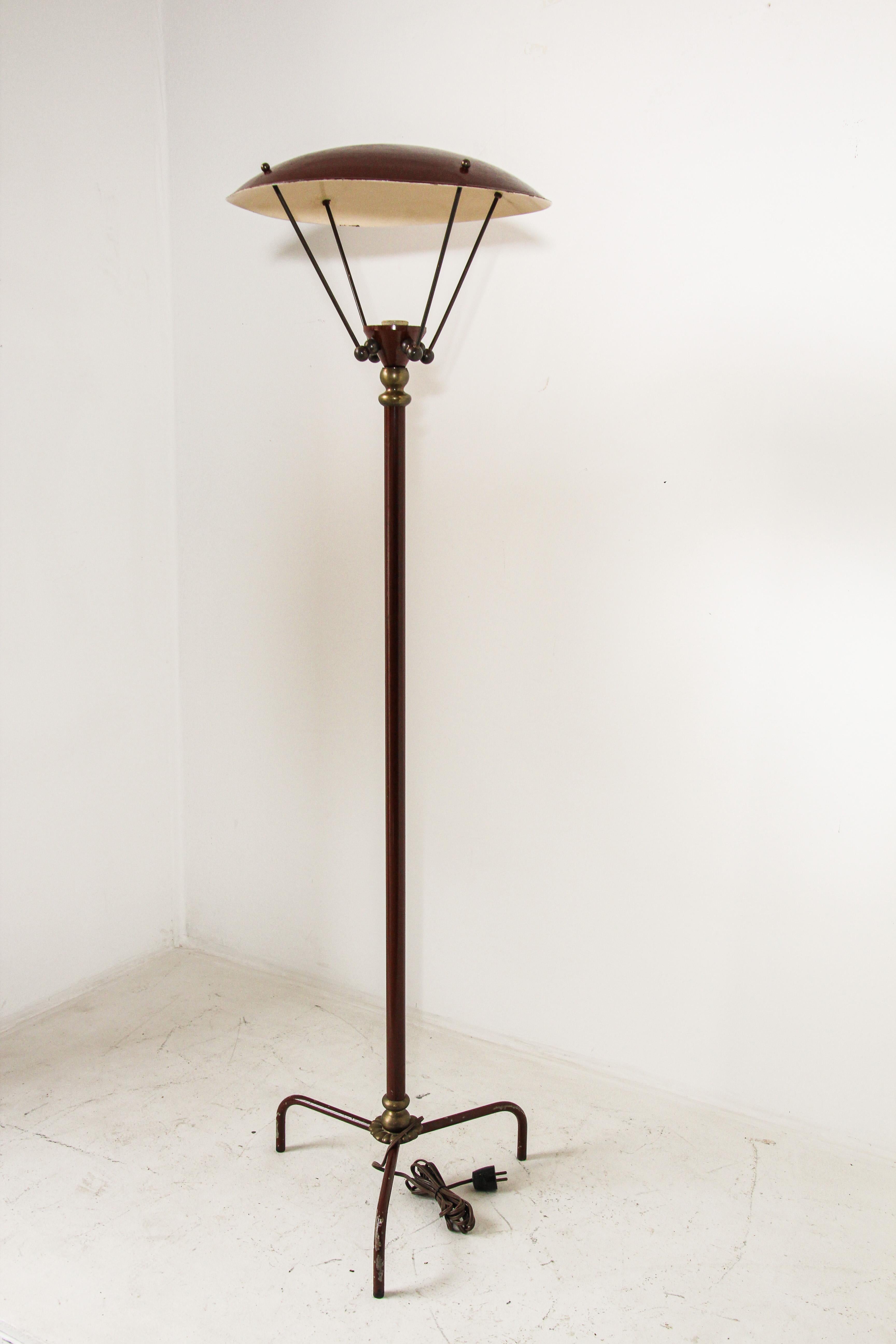 A Sculptural vintage French tripod floor lamp with brass details and iron frame.
Substantial midcentury vintage brown enamel and brass floor lamp from the 1950s.
Architectural, sculptural, statement lighting featuring a tubular brown central column,