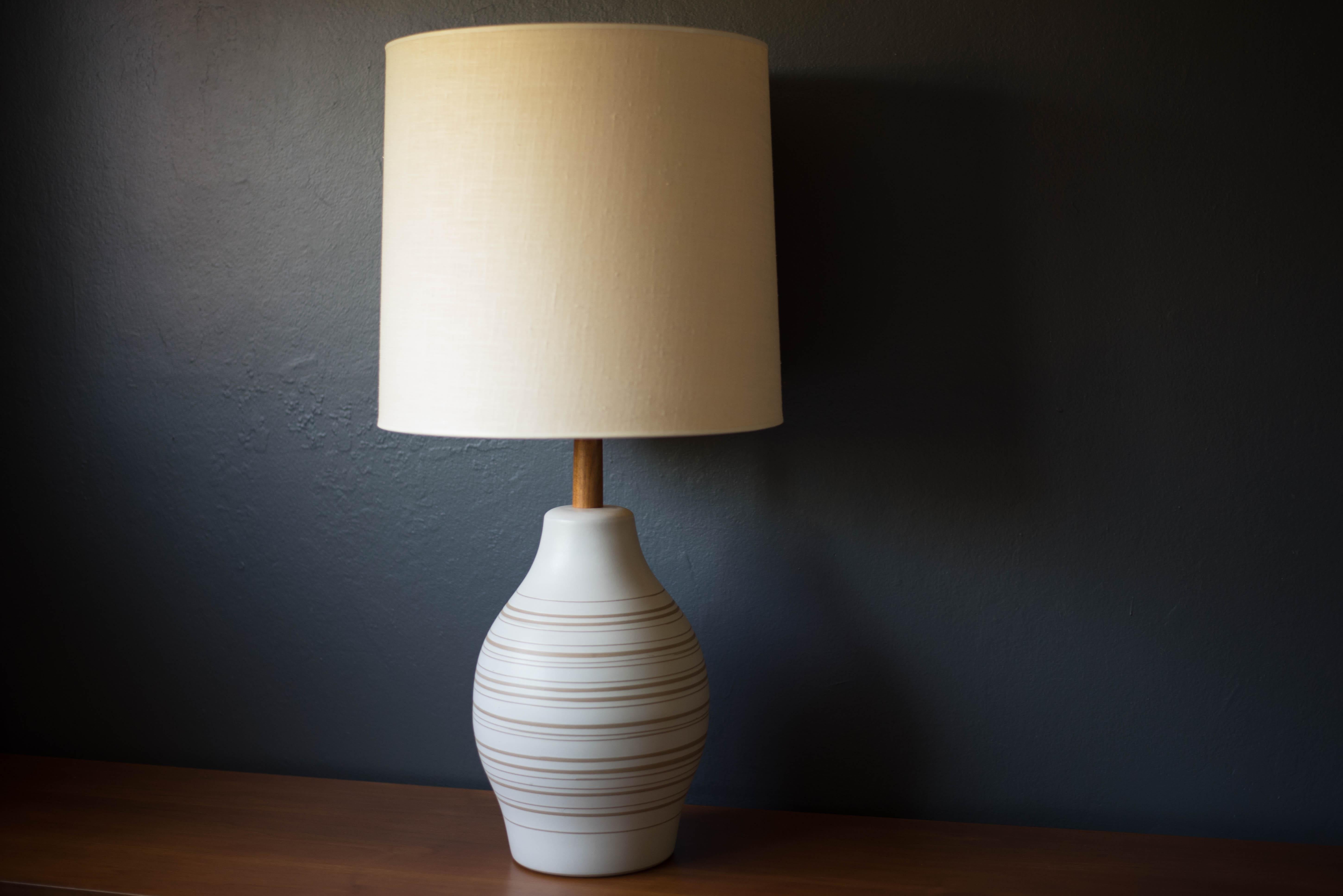 Mid-century sculptural accent table lamp designed by Jane and Gordon Martz for Marshall Studios. This piece features a matte white ceramic base with natural incised lines. Complete with the signature black walnut finial and three-way switch