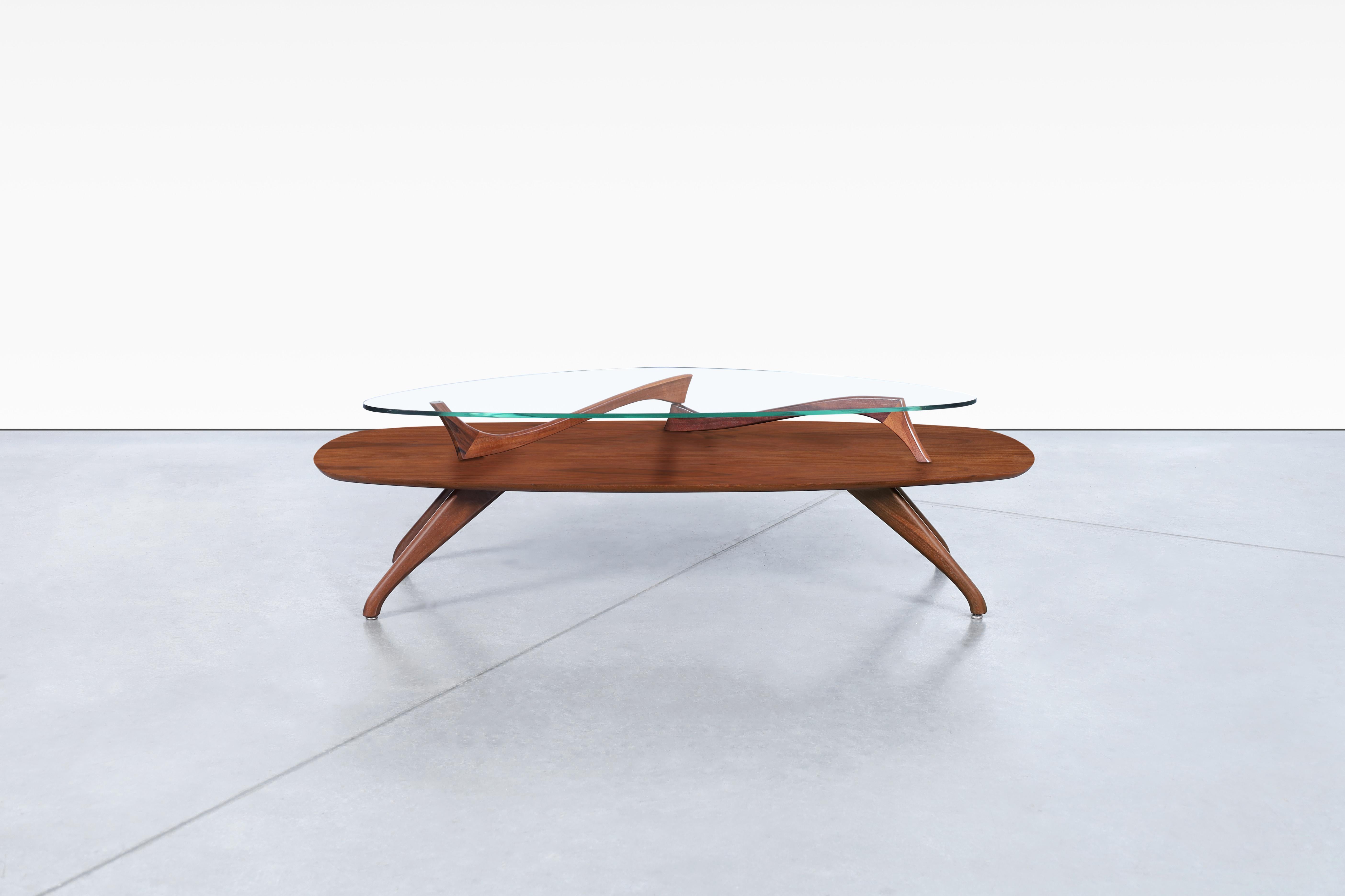 Cette étonnante table basse sculpturale vintage en noyer est un véritable chef-d'œuvre de design. Sa structure à deux niveaux comprend un grand plateau en forme de planche de surf en bois de noyer magnifique, avec un détail en noyer massif pris en