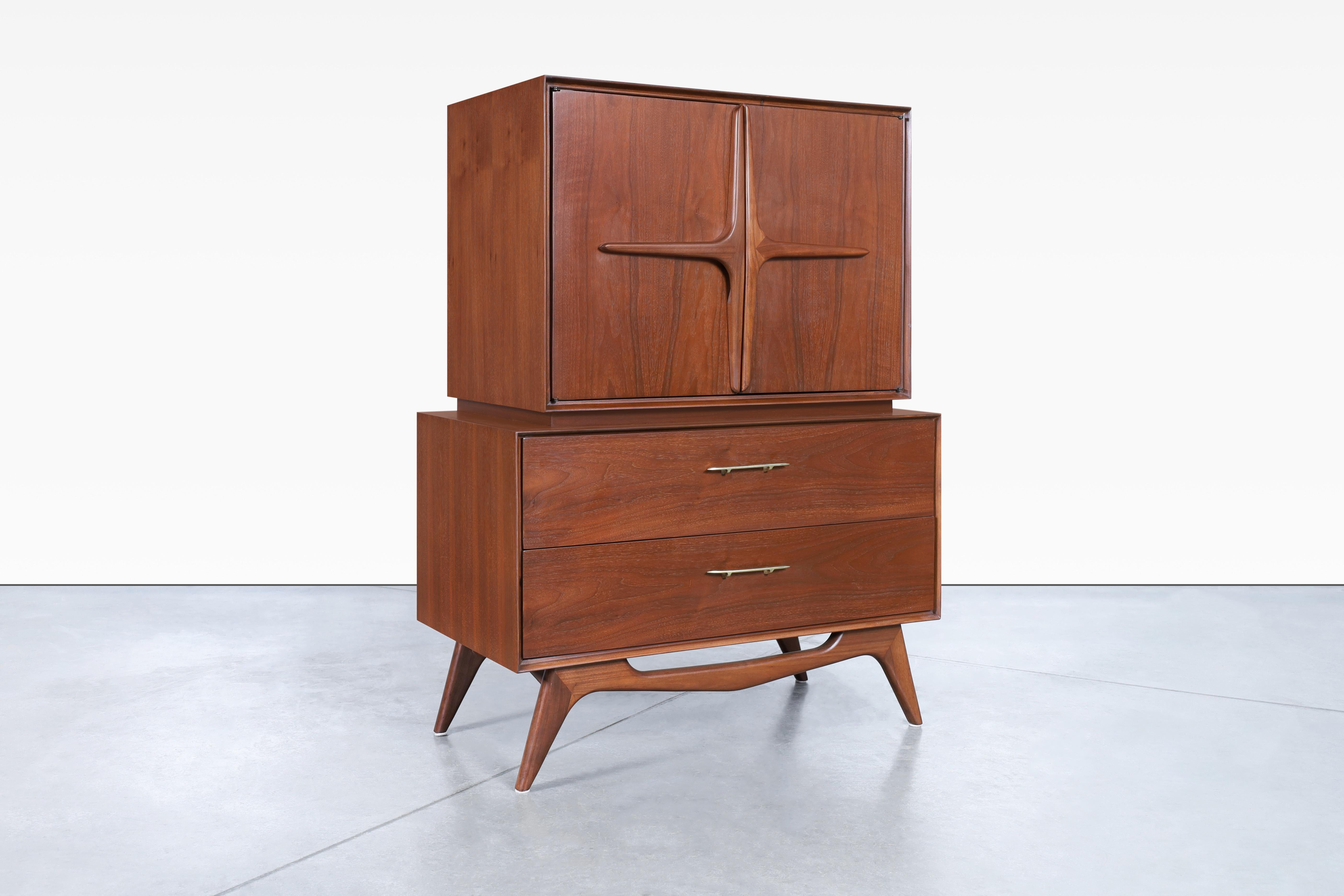 Vintage sculptural walnut high-boy manufactured in the United States. This exquisite highboy is crafted from premium quality walnut wood and boasts a daring design that will definitely make a statement in any room. The brass handles, along with the