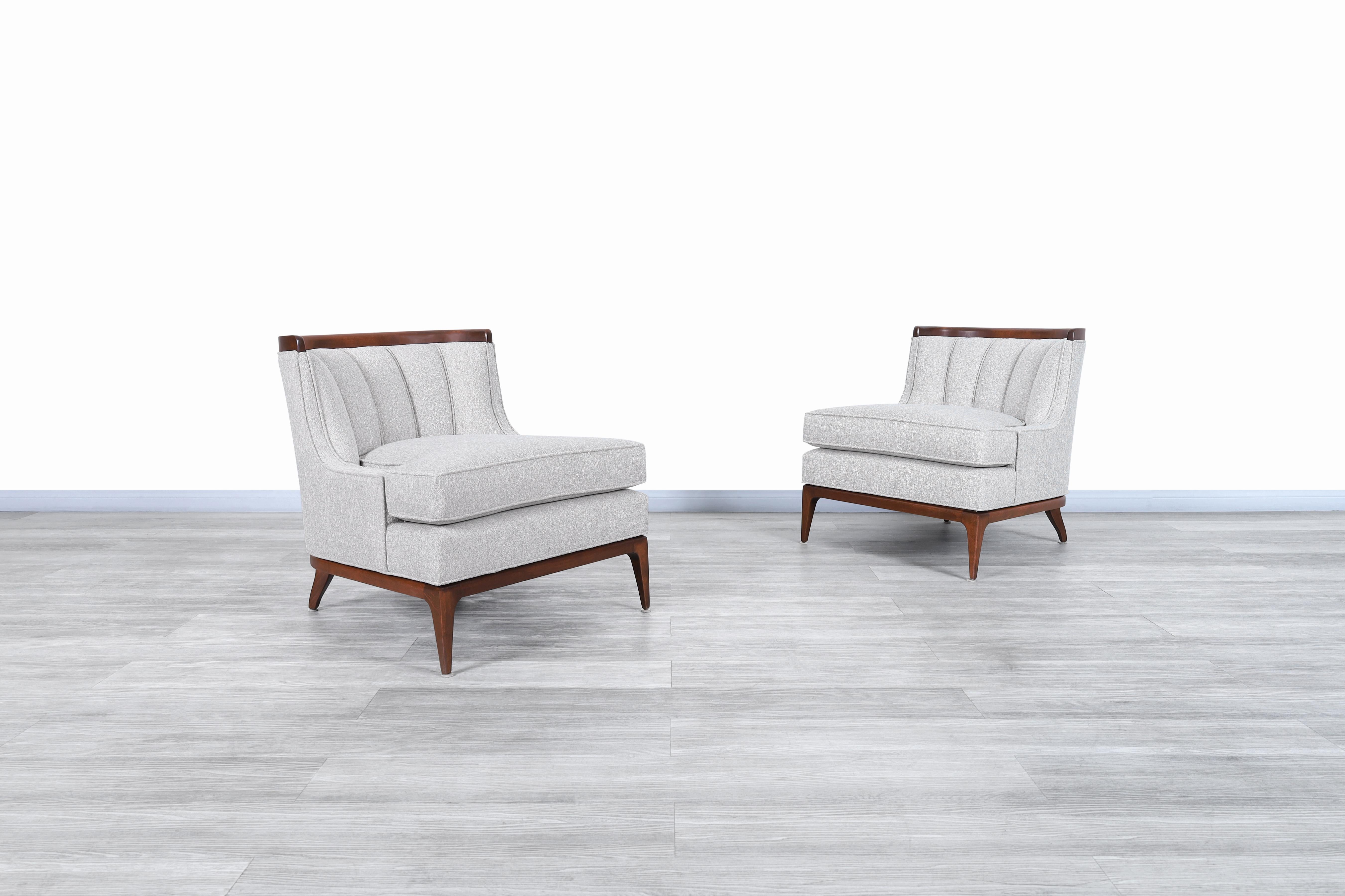 Wonderful pair of vintage sculptural walnut lounge chairs in the manner of Erwin Lambeth and manufactured in the United States, circa 1950s. These incredible chairs feature solid walnut details that surround the chairs, and in addition to this, the