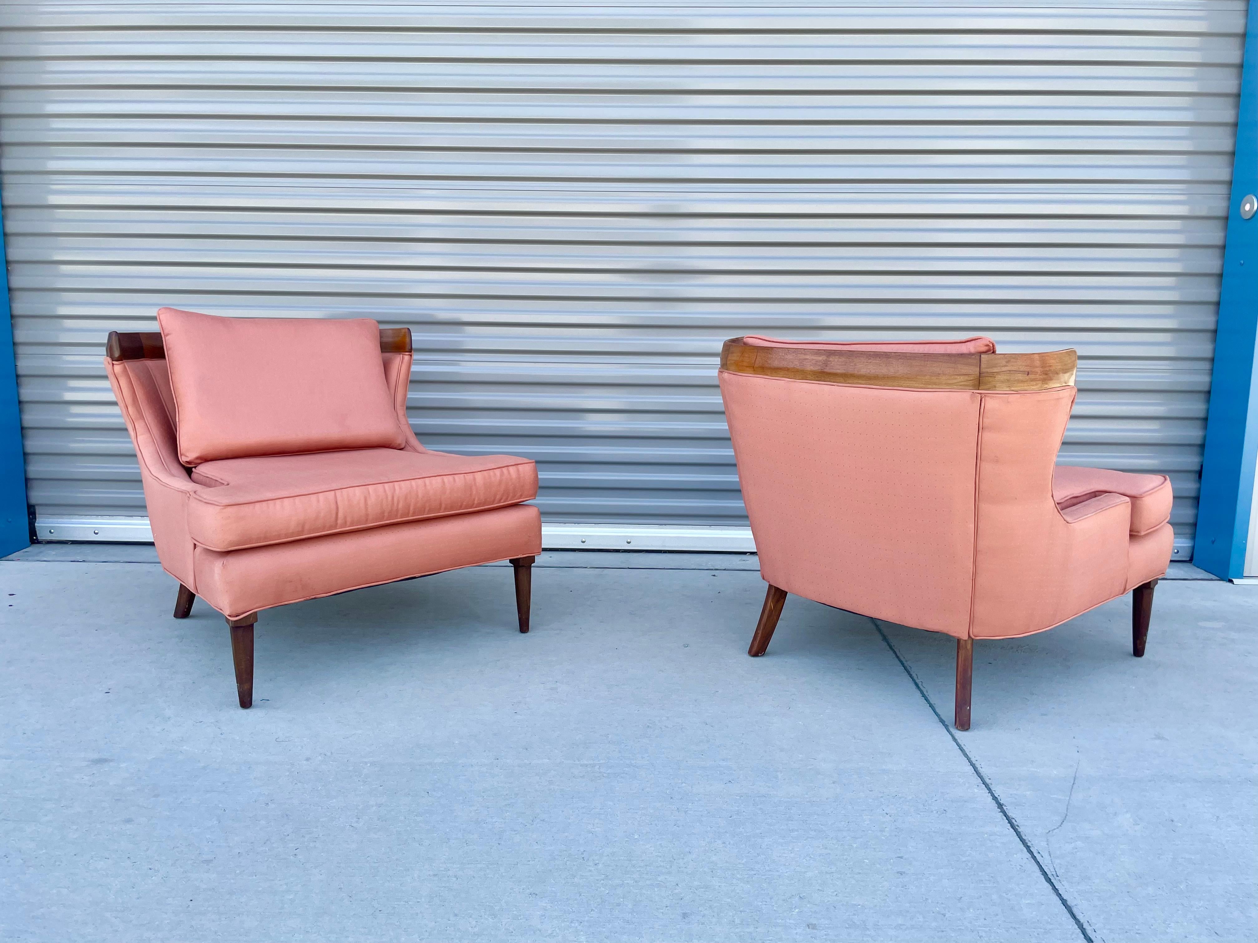 Wonderful pair of vintage sculptural walnut lounge chairs in the manner of Erwin Lambeth and manufactured in the United States. These pair of chairs feature a curved walnut design giving that perfect vintage style to it. The chair comes with a pink