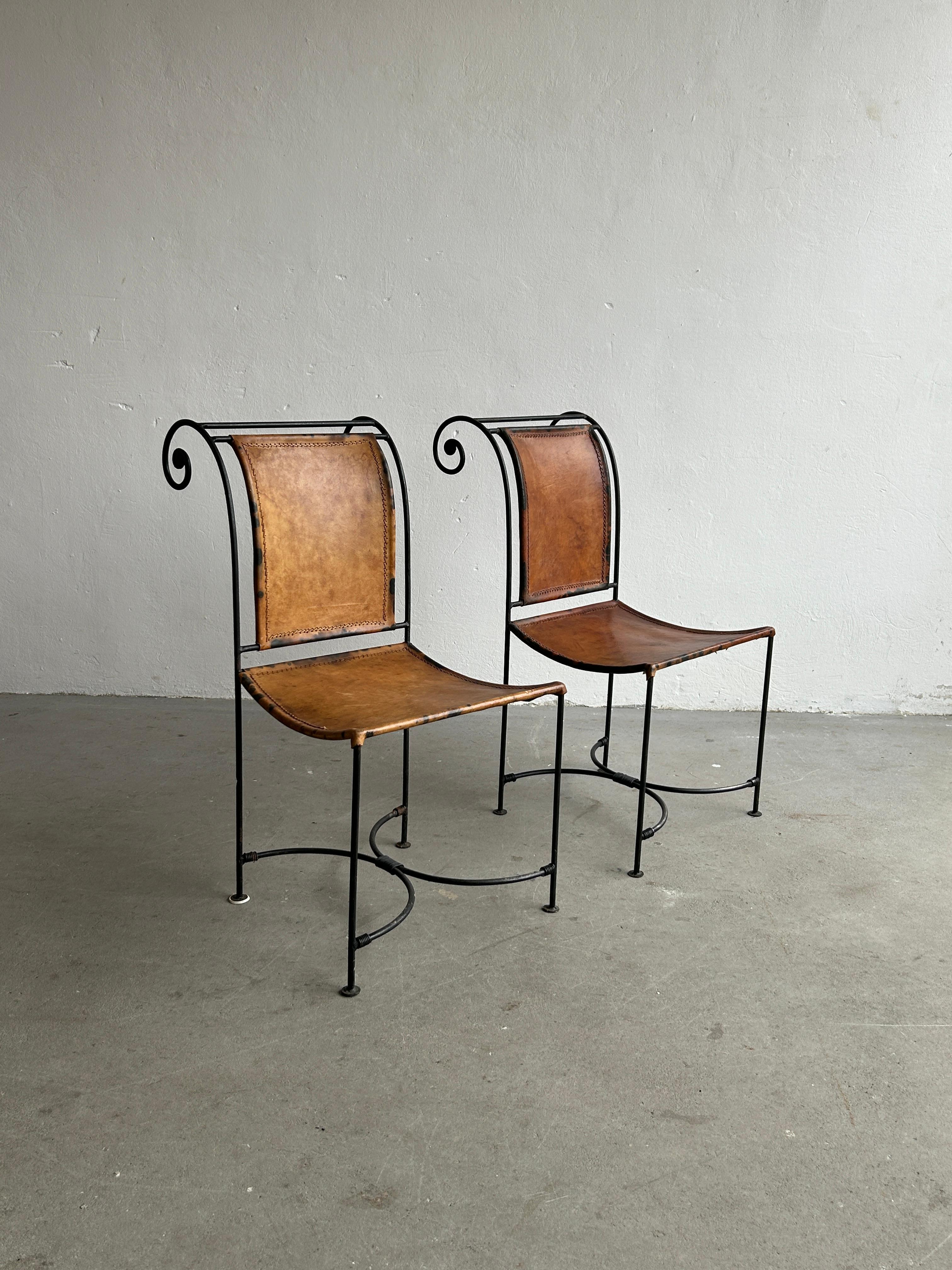 A pair of vintage sculptural accent chairs, made from swirl shaped wrought iron and thick leather seat and backrest, 1950s handcrafted production following the Mediterranean or Spanish Colonial design style.

In original vintage condition, with