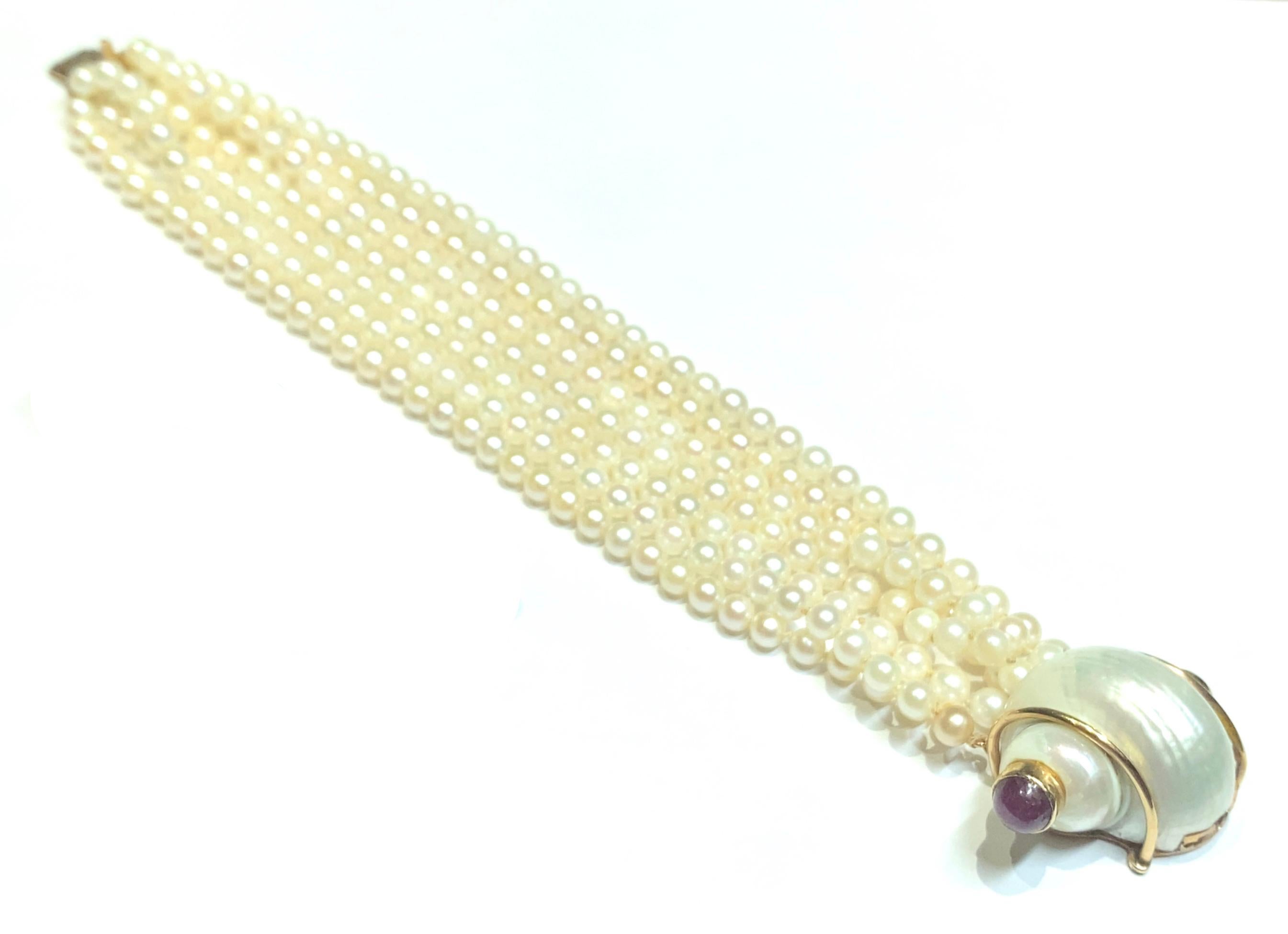Vintage Seaman Schepps 7 strand pearl bracelet with 18k iconic shell clasp with 2 cabochon rubies weighing approximately 2.50 carats.