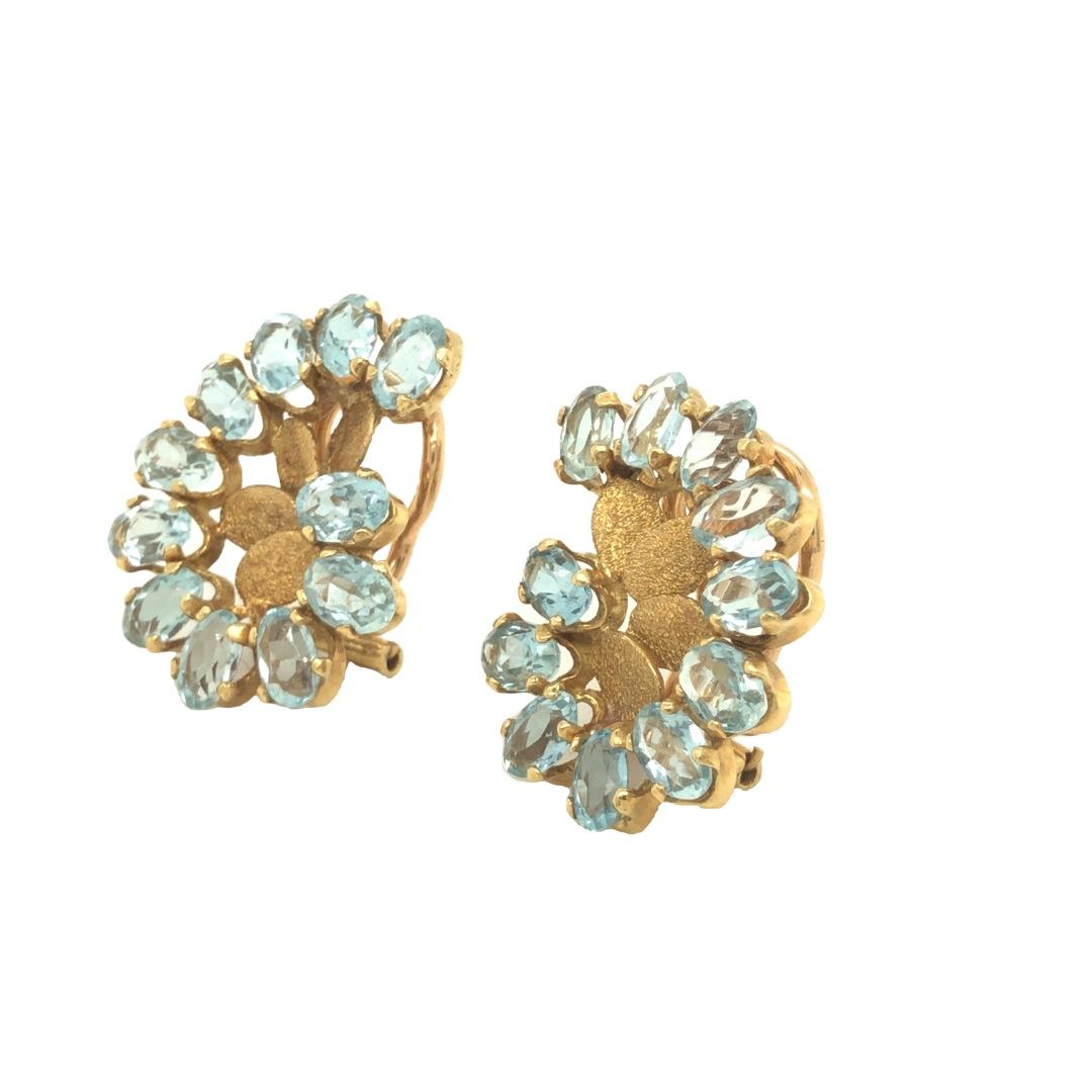 Seaman Schepps 18K Yellow Gold Aquamarine Swirl Earrings showcasing faceted oval shaped aquamarine, accented by textured gold leaf petals. Total estimated weight of aquamarine is 7.30 carats. Gross gold weight 12 grams. The earrings measure 3/4 inch