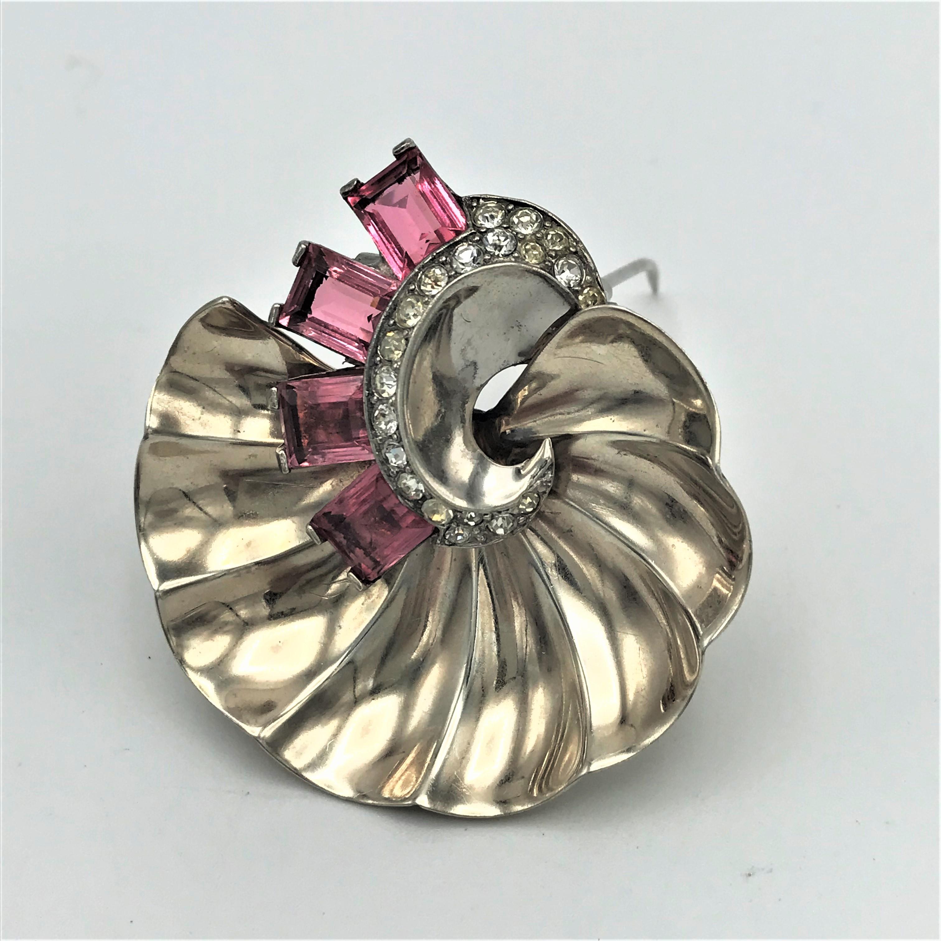 A beautiful pin brooch / clip with 2 barbs in the shape of a shell. The shell is decorated with 4 cut rectangular pink colored and clear rhinestones. 
Measurement:
Diameter 4,5 cm,  the pink rhinestones 0.8 cm x 0,5 cm, Sterling silver gold plated,