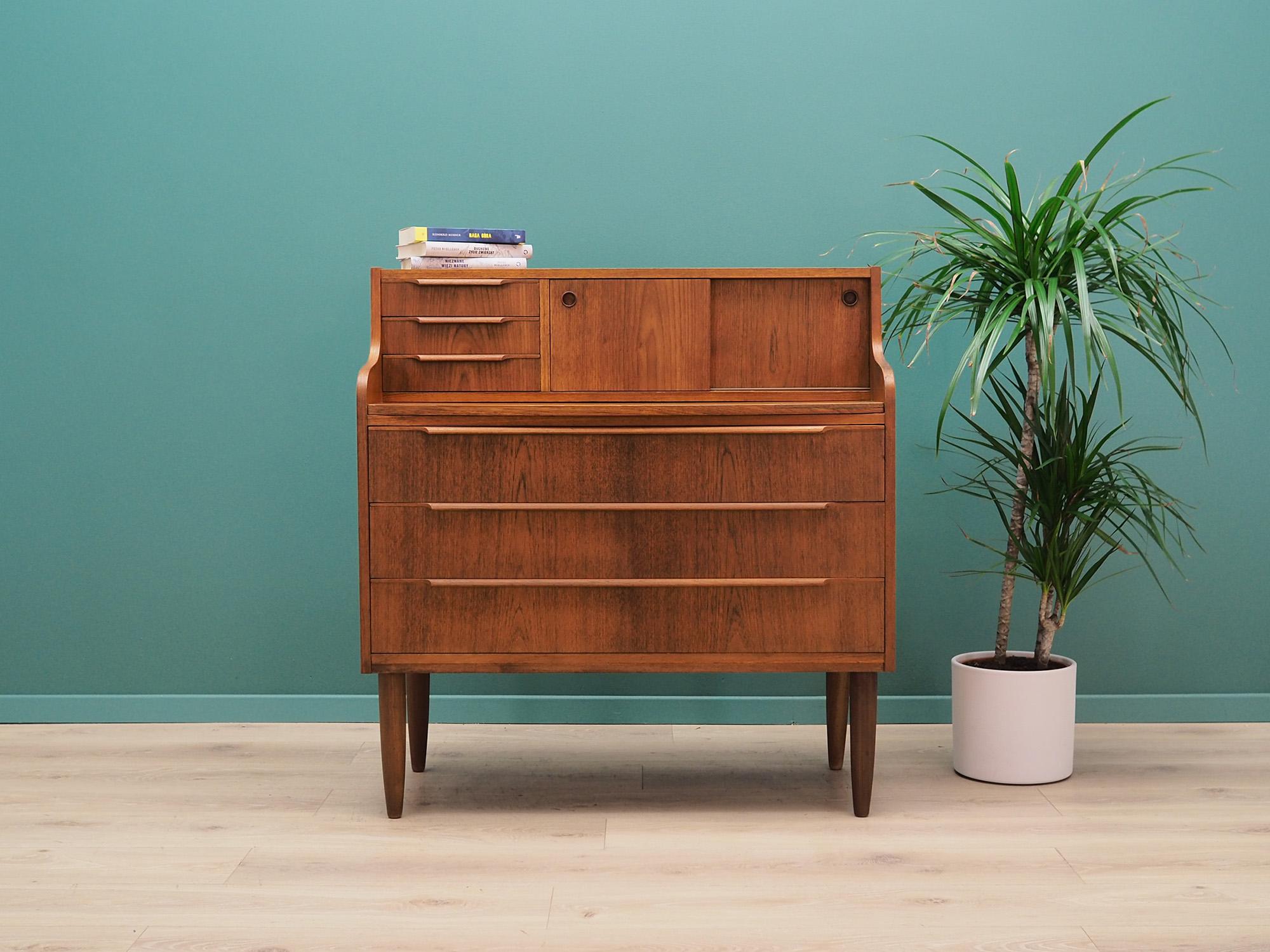 Fantastic secretary from the 1960s-1970s. Scandinavian design, Minimalist form. Furniture covered with teak veneer, legs made of solid teak wood. Secretary has three capacious drawers under the retractable top, above it there are three stylish
