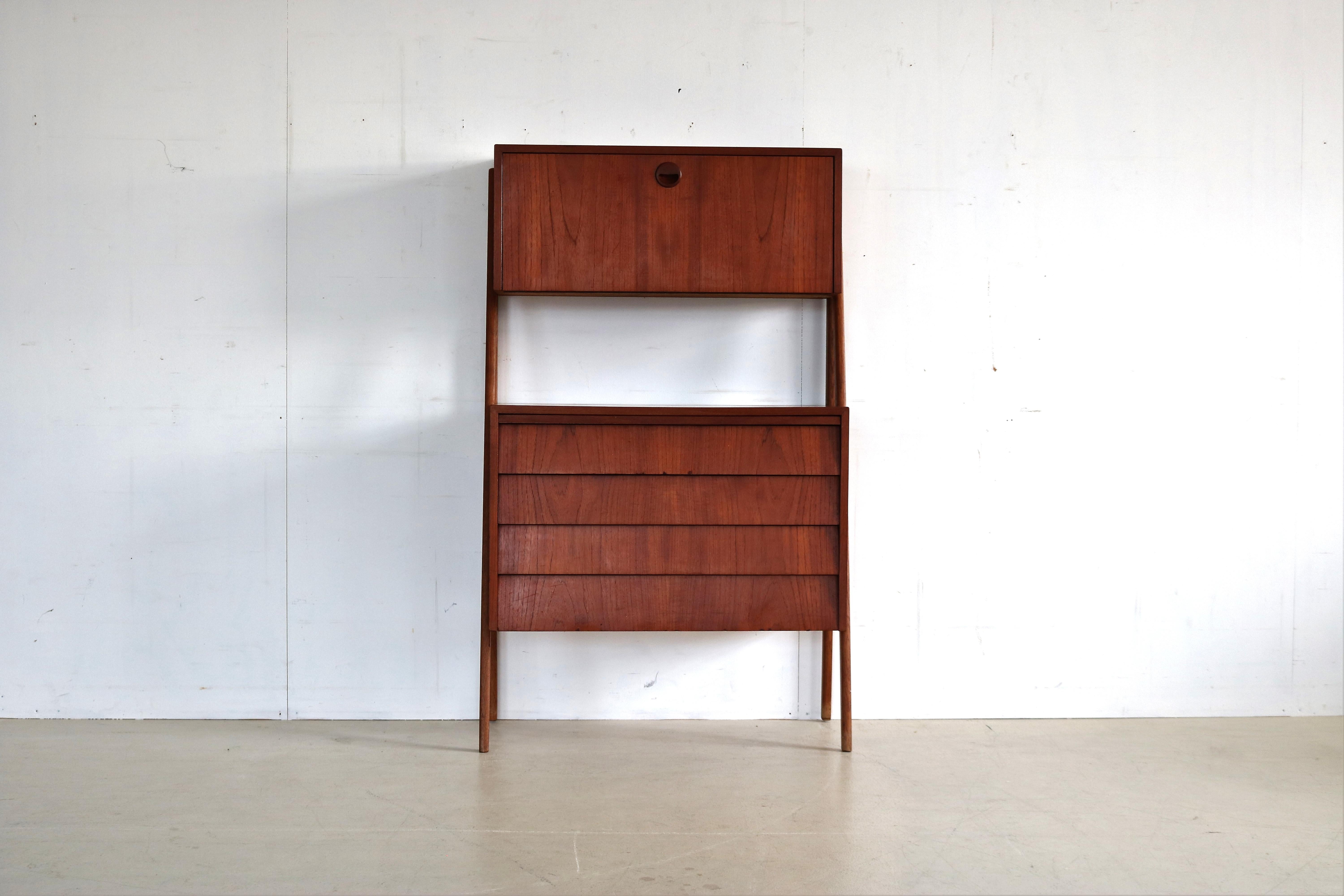 vintage secretary wall cabinet teak, 1960s, Denmark

Multifunctional cabinet from the 1960s. This wall cabinet in teak version with oak legs can be used as a desk by means of an extendable worktop. Behind the opening flap is storage space with a