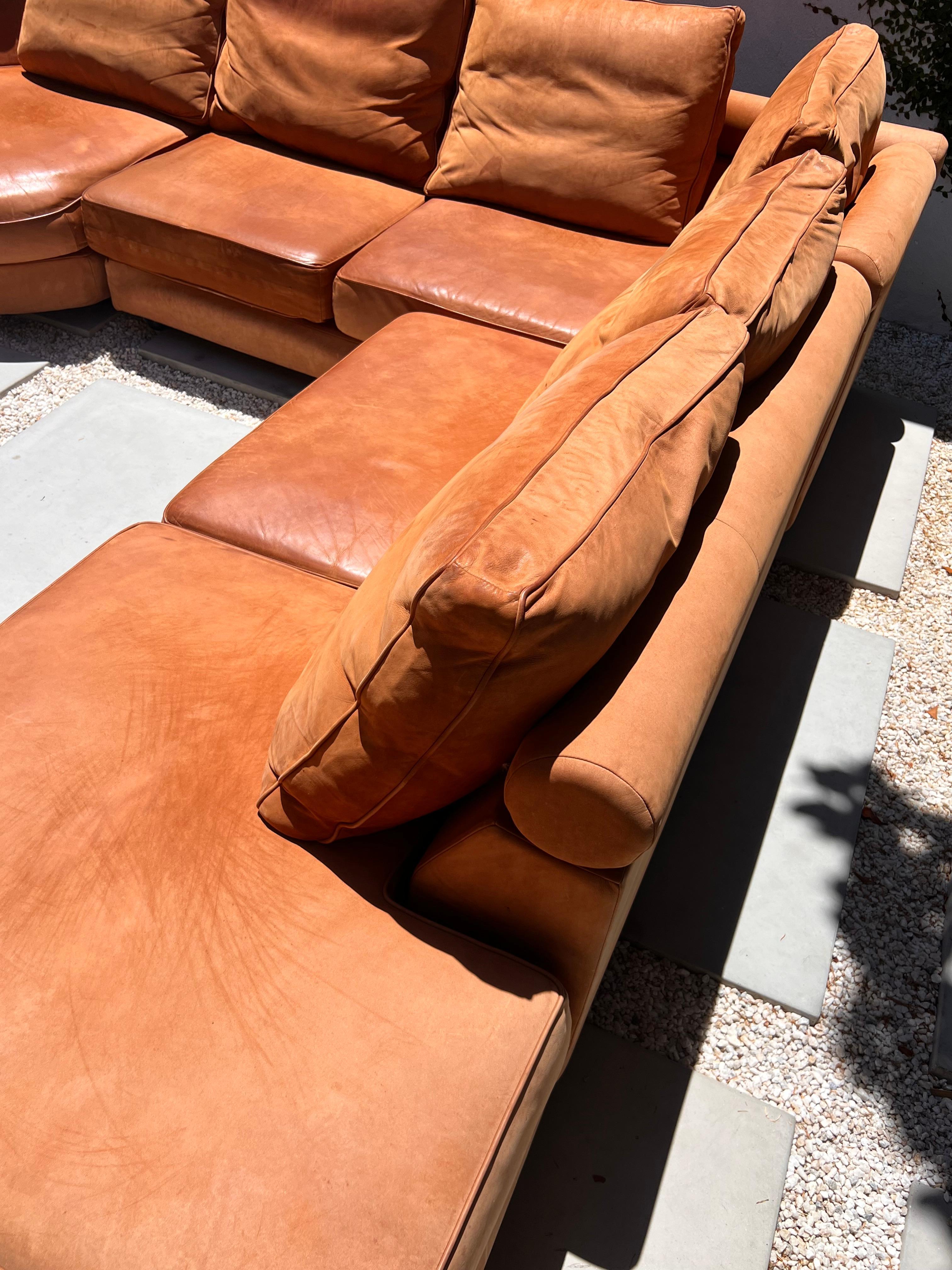 A modular sectional sofa in cognac leather by Roche Bobois, France late 20th century. This iconic sofa is composed of three pieces which can be arranged a number of ways, outfitted in sumptuous soft cognac leather, and adorned with six original