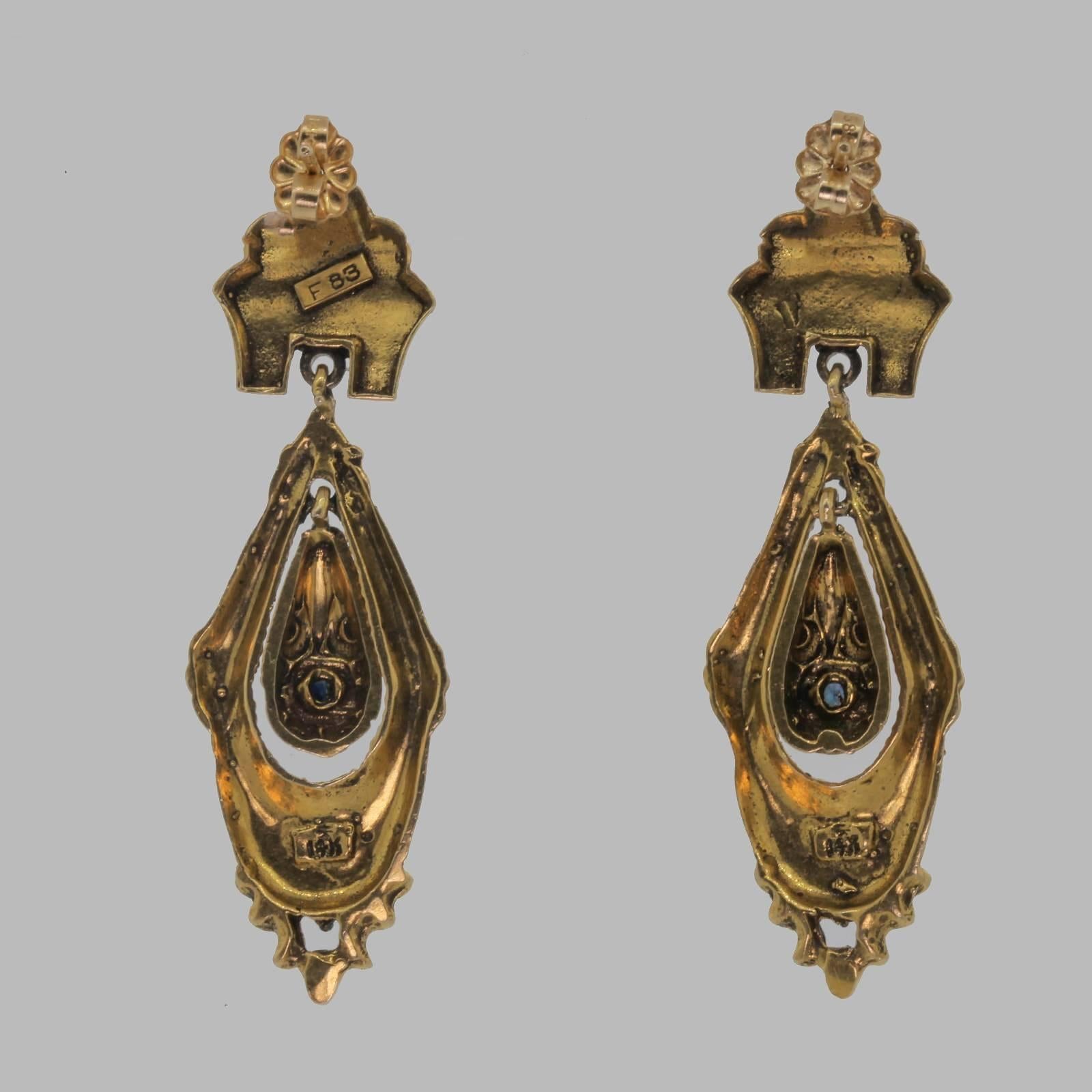 Regency revival vintage drop 14KT yellow gold earrings.  The elongated drops are accented in the center with a blue Sapphire and Seed Pearls at the bottom of the dangles.  The 2 inches long earrings are enhanced with engraving designs and stamped
