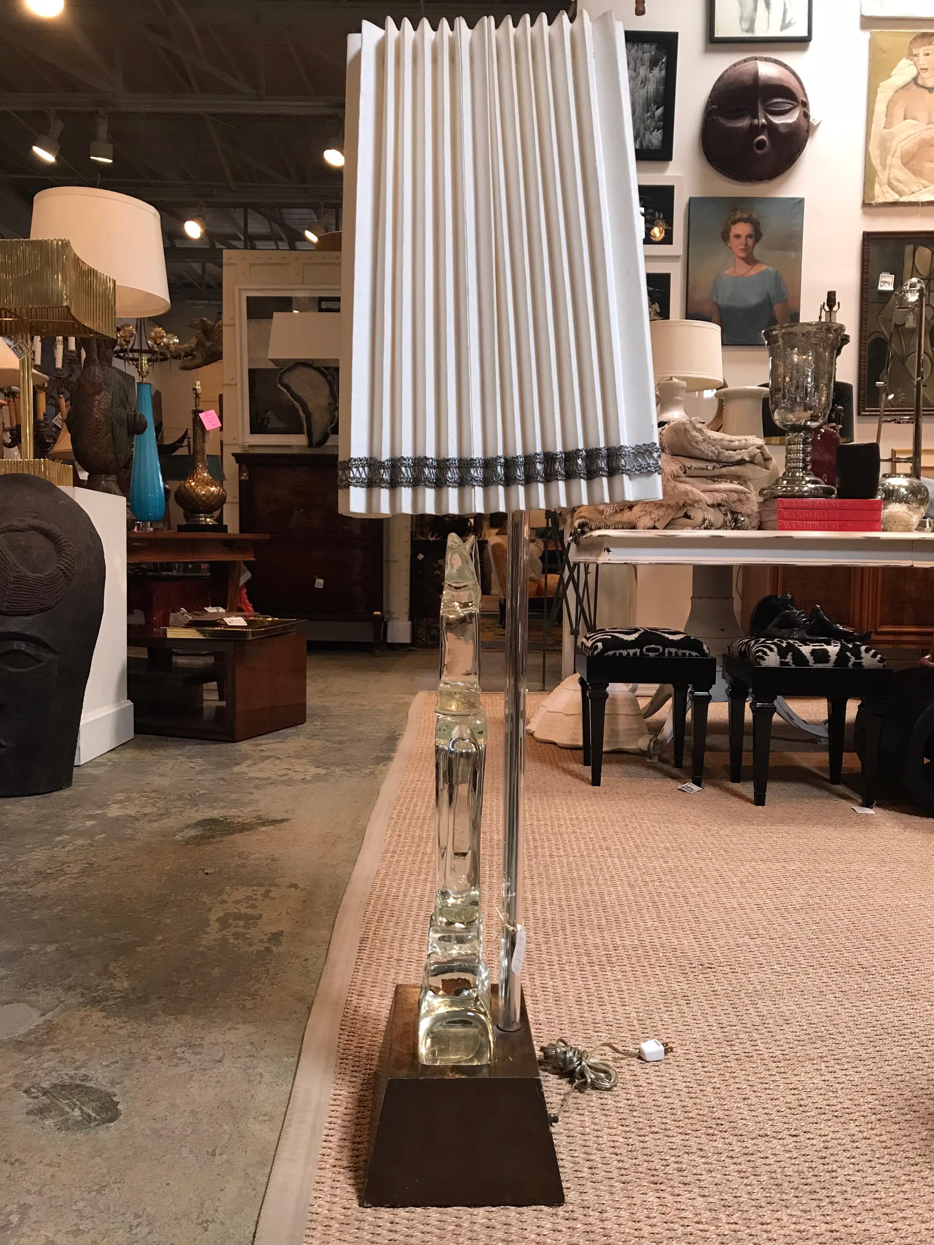 This Seguso Murano lamp has a glass figure form that sits ontop of the brown wooden base with a bulb beneath it to light the Murano glass when turned on separately by a switch in the back. The off-white shade is long and riffled with intricate