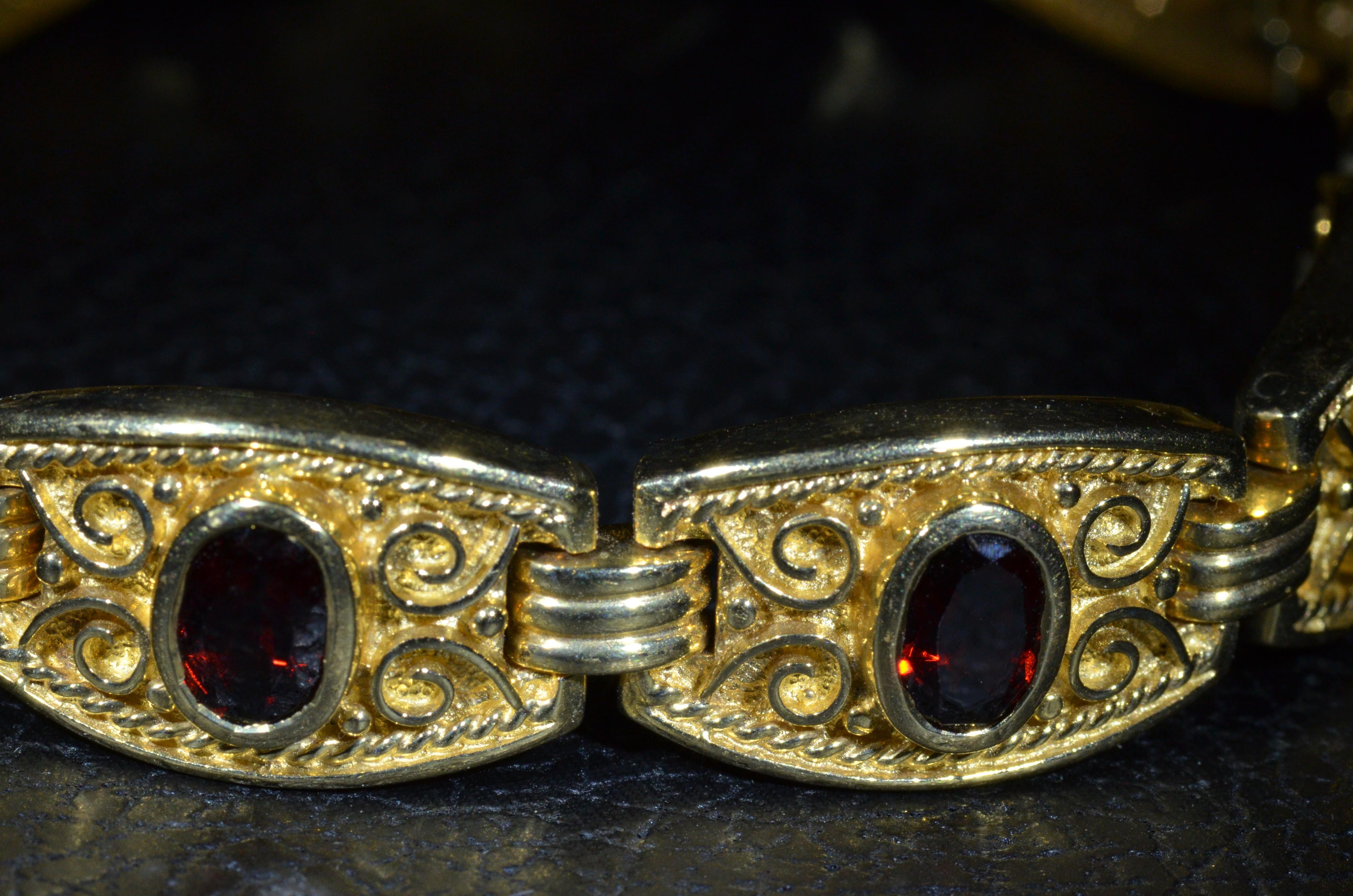 Vintage SeidenGang Retro Bracelet set with 9 Carats of Garnets.  The bracelet features specialty clasp and nine bezel set 1.00 carat Spessartite Garnets.  On either side of the center bezel set spessartite garnet is a scroll like pattern and outer