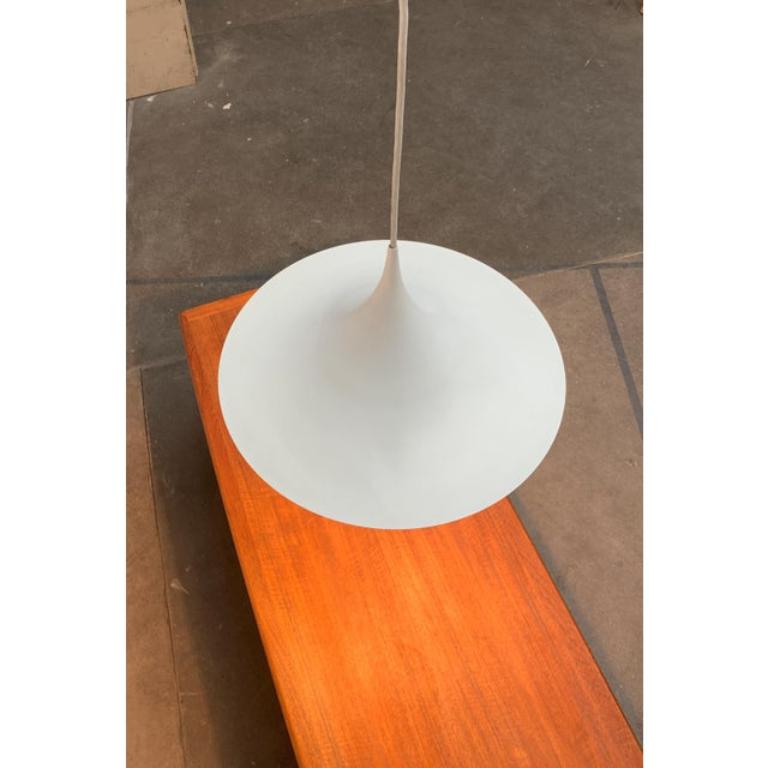 Semi pendant light in white.

Elegant shape, narrow in profile. The entire shape of the luminaire screen runs together in a finely executed tip, which passes seamlessly into the cable. The light is directed directly downwards. This luminaire is an