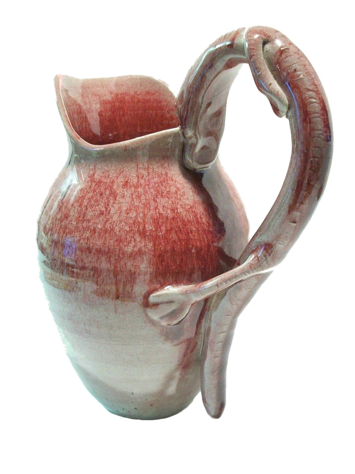 Vintage serpent handled wheel thrown studio pottery pitcher - elegant proportions - dramatic presence - hand modeled serpent clutching the edge of the vessel with its' mouth - the hind legs and tail fall to the base - a swirl of turquoise glaze to