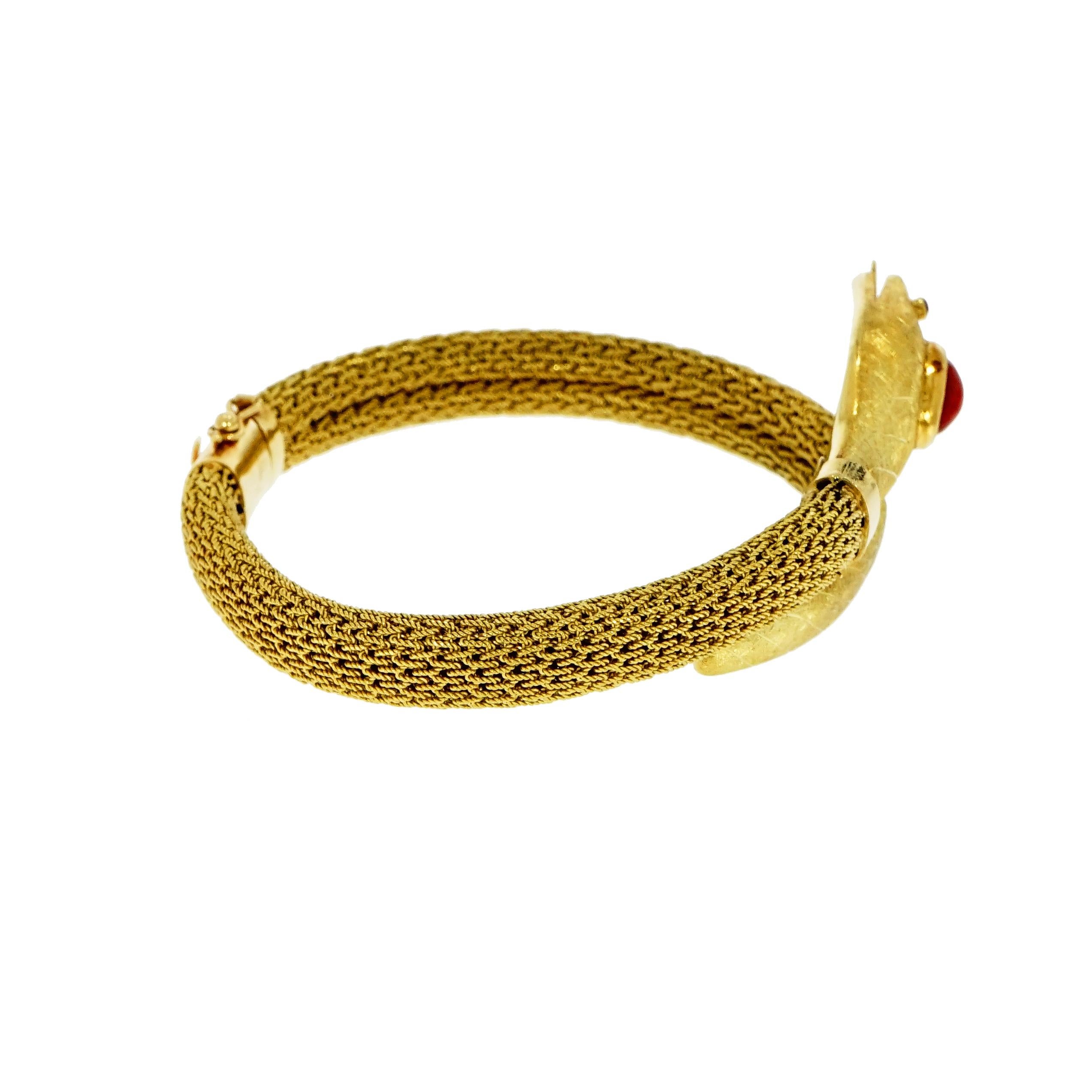 This Vintage Serpenti Bracelet is Crafted in Italy, in 18K yellow gold. 
The head of the snake has a three-dimensional design with ruby eyes, carrying an oval cabochon Mediterranean Coral as crown, a parted tongue that peeks out from its mouth. 
The