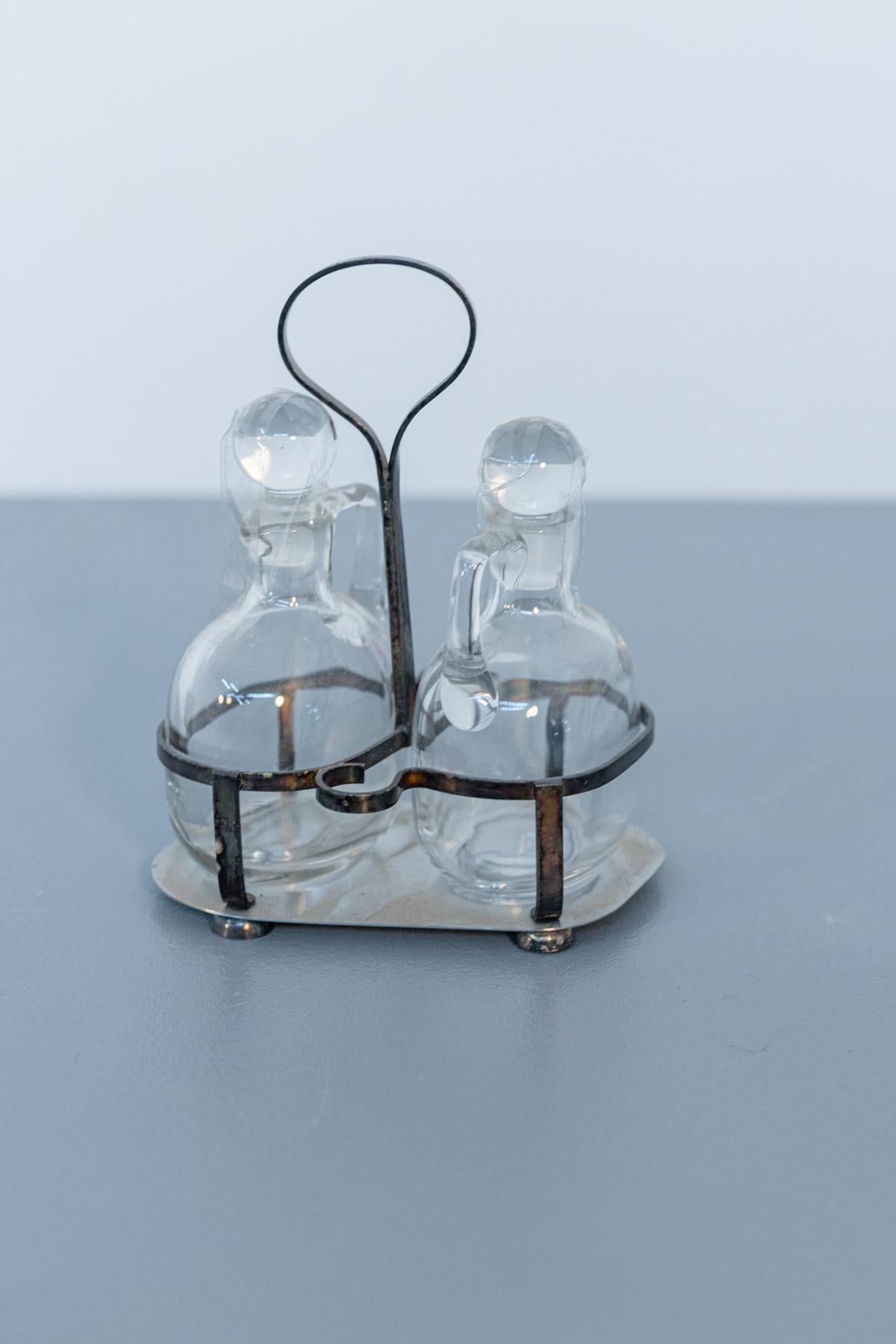 Beautiful glass oil and vinegar service designed in style of Gio Ponti in the 1950s, Italian made.
The set is made entirely of glass and the supporting base is metal. The bottles have a sinuous and round shape, even the cork is topped with a glass