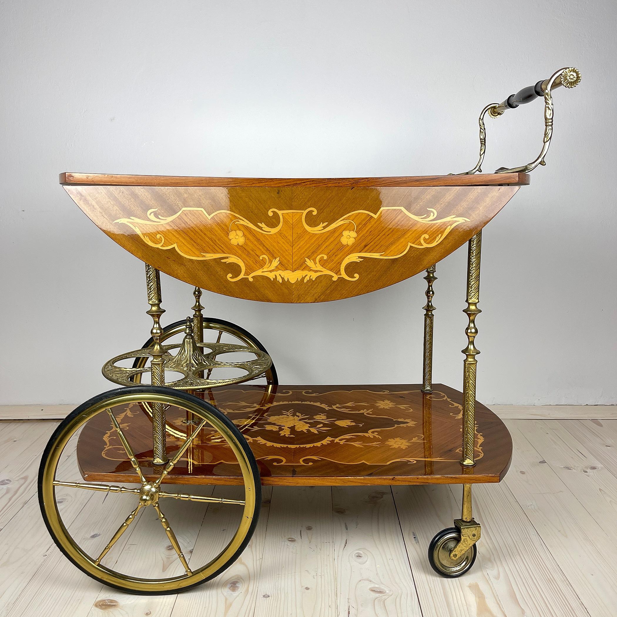 Vintage Italian bar cart with marquetry inlay on 4 wheels. This cocktail bar drinks cart was made in Italy in the 1950s Hollywood Regency style. Thanks to the ornate woodwork, the cart is a real craftsmanship. It has floral and scroll work inlay.