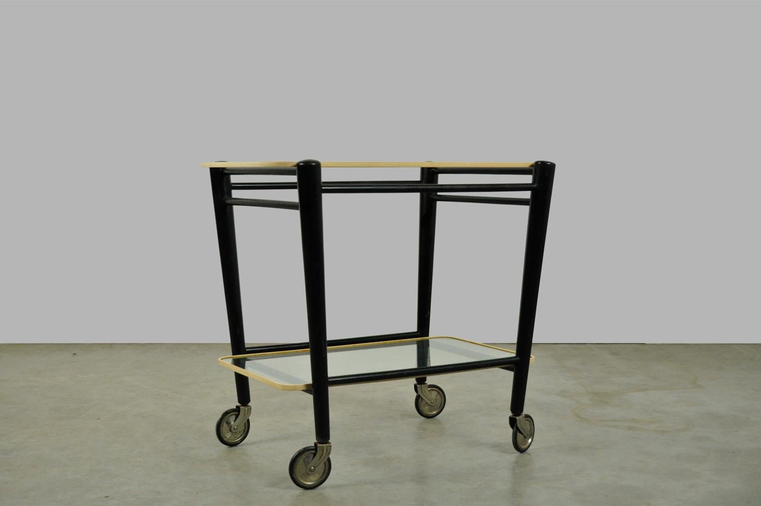 Vintage serving trolley designed for the former Coja furniture factory in Culemborg, 1950s. The tea cart has a frame of black stained wood (original) containing two loose glass plates with rounded corners and plastic protective edge. The bar cart