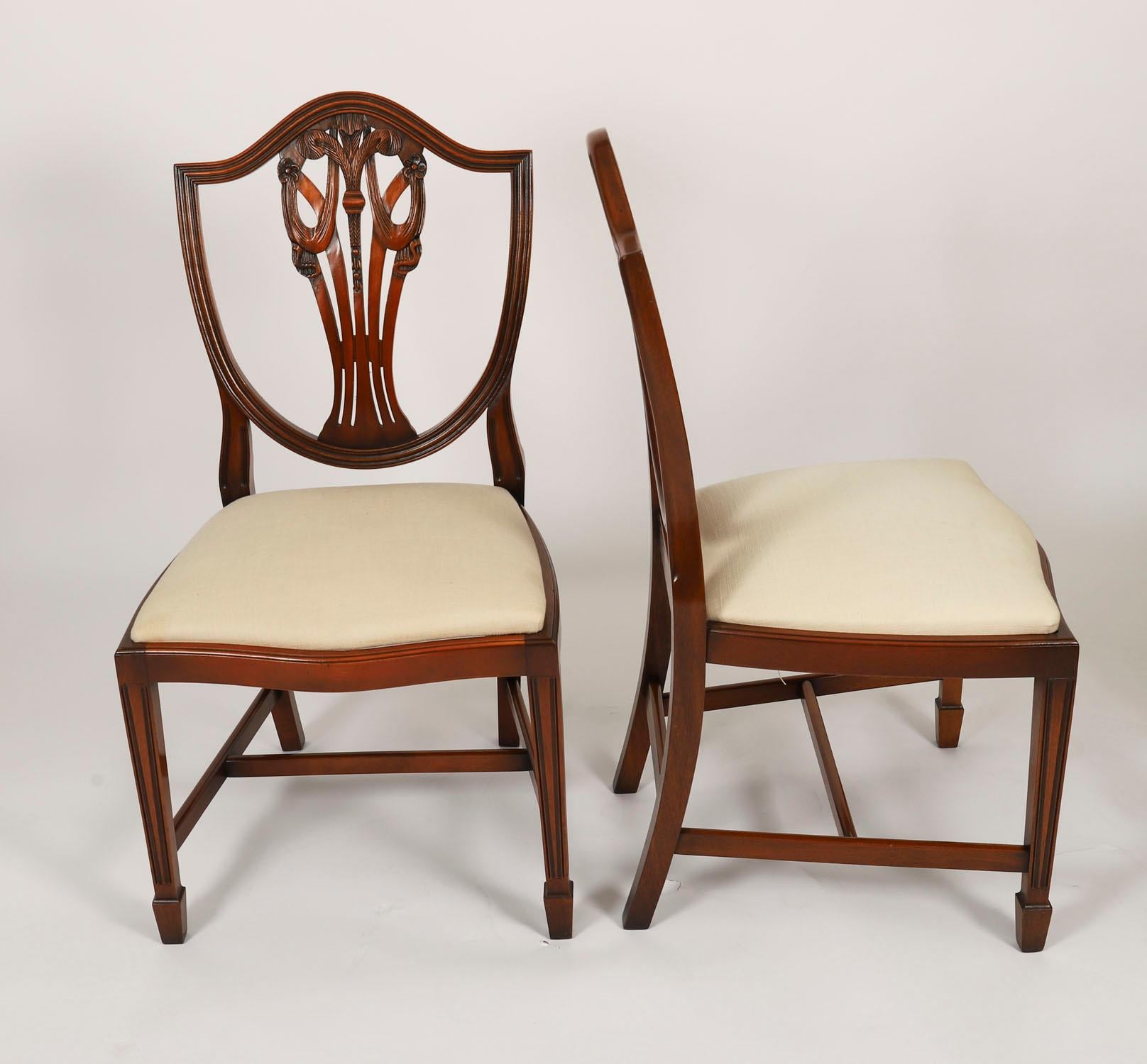 Il s'agit d'un fantastique ensemble de douze chaises de salle à manger Hepplewhite Revival, de fabrication anglaise, datant du milieu du 20e siècle.

Ces chaises ont été fabriquées de main de maître dans un magnifique acajou massif. La finition et