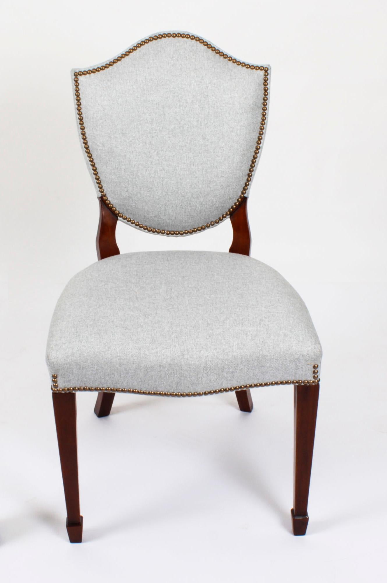 Ein hervorragender Vintage-Satz von zwölf Hepplewhite-Revival-Esszimmerstühlen mit gepolsterten Rückenlehnen, die aus der zweiten Hälfte des 20.

Das aus massivem Mahagoni handgefertigte Set besteht aus zehn Beistellstühlen und zwei Sesseln, die