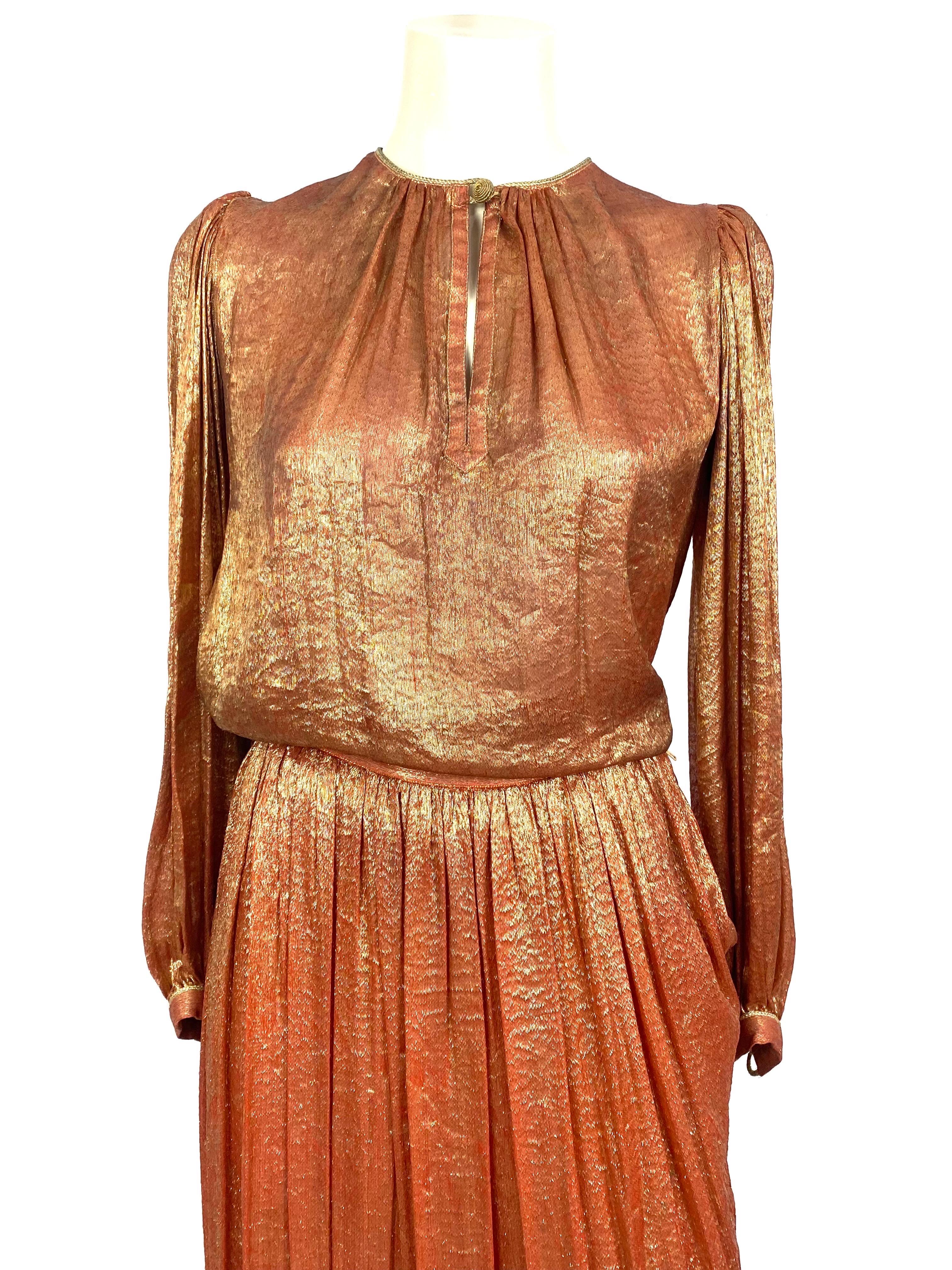 Stunning vintage 2-piece set from 1976 by Yves Saint Laurent in gold and bronze silk lamé, Slavic inspiration.
The blouse, balloon sleeves and pleats on the shoulders, round neck closing with a pretty twisted trimming button and a teardrop