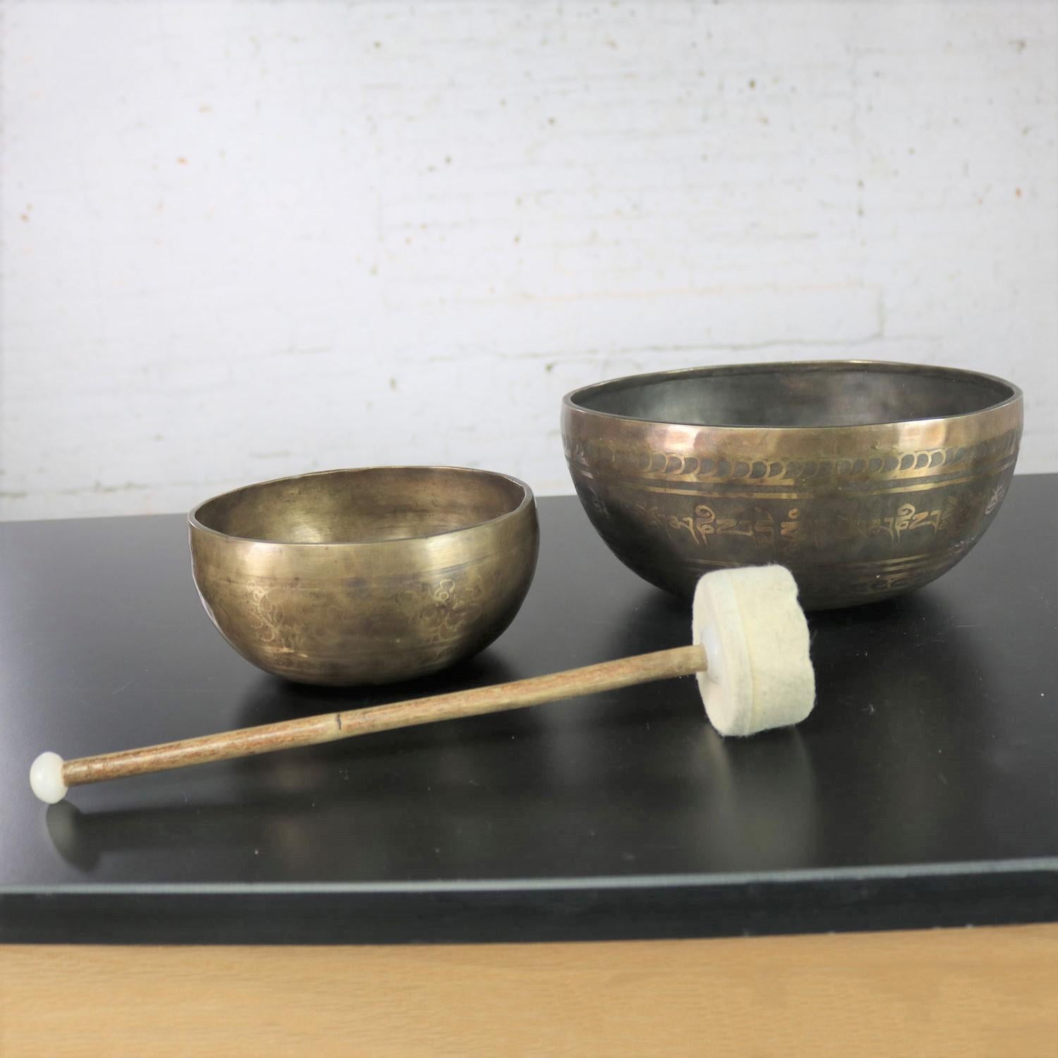 Handsome set of 2 nesting singing bowls or standing bowls a mallet for playing. Handmade of bronze or bell metal having an incised design on each bowl. They are in wonderful vintage condition and have awesome patina. Please see photos, circa 20th