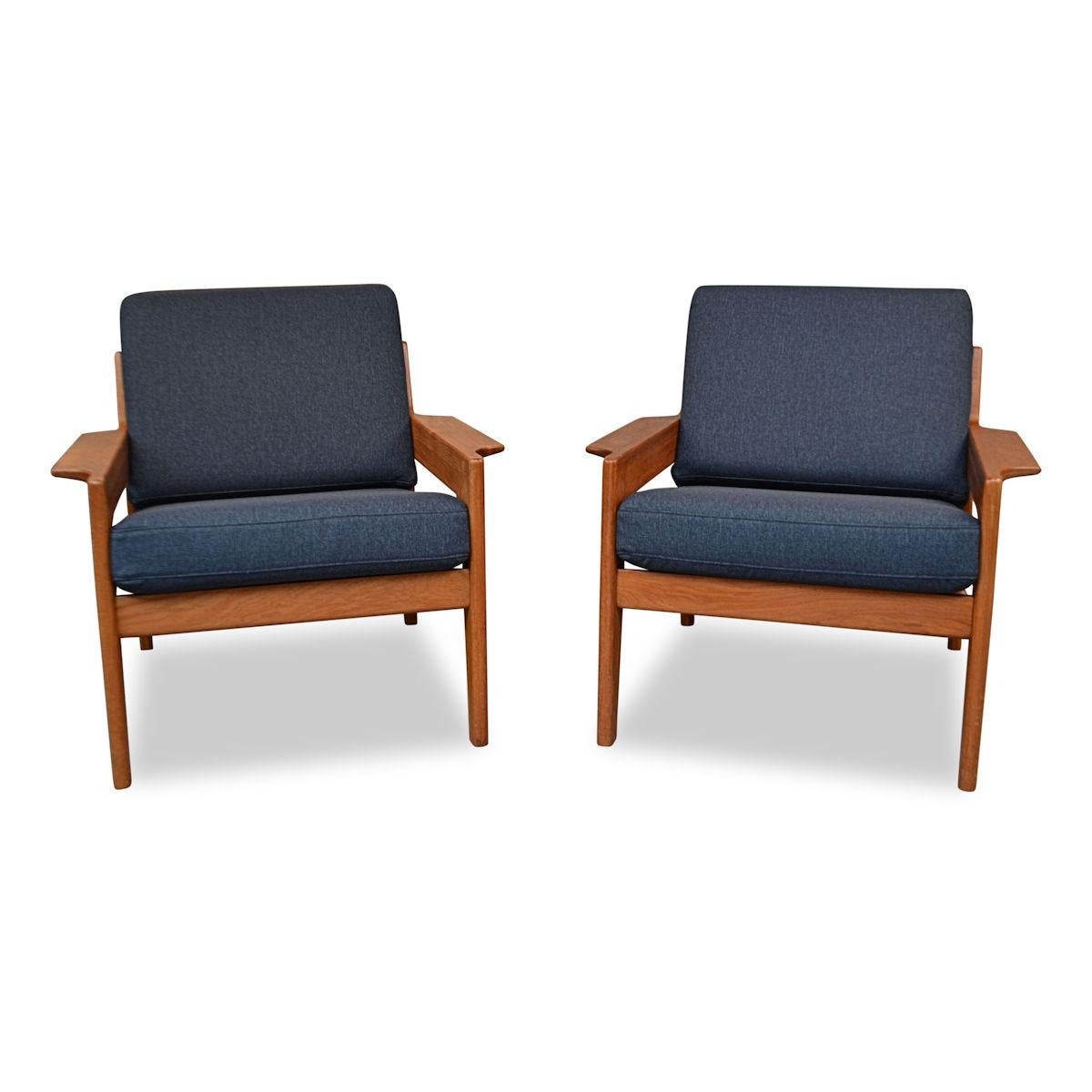 Stunning pair of vintage teak lounge chairs designed by Danish designer Arne Wahl Iversen for Komfort. These Mid-Century Modern lounge chairs feature a stylish 1960s design, a beautiful solid teak frame, comfortable seating and new navy blue