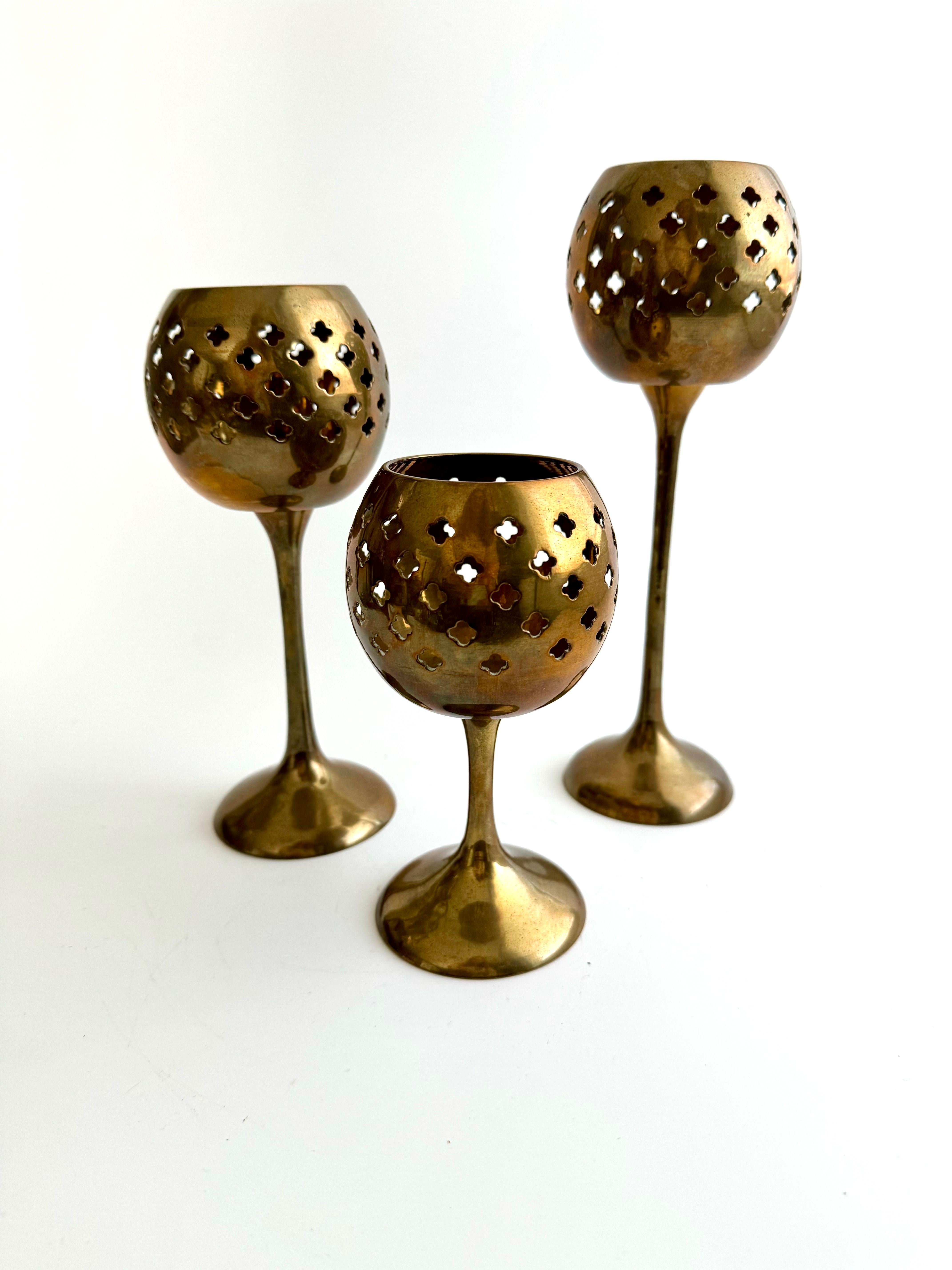Illuminate your space with the warmth of a bygone era. This exquisite set of three vintage votive candleholders brings the timeless elegance of Indian craftsmanship to your home. Hailing from the rich cultural heritage of India, each piece has been