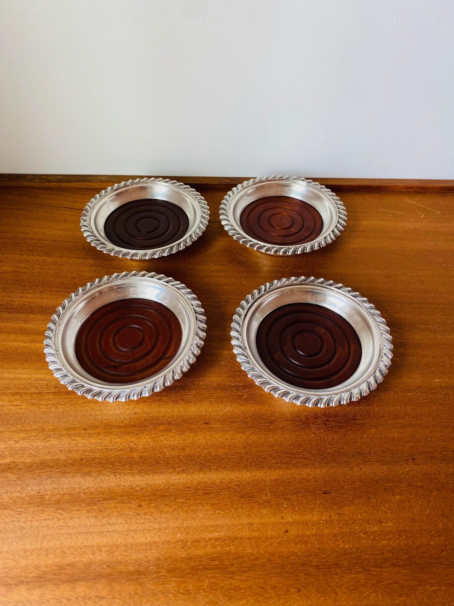 Bonito y elegante juego de 4 posavasos plateados.  Cada posavasos consta de una base de madera vintage rodeada de una corona plateada.  Cada pieza aporta glamour y presencia del viejo Hollywood.  Apiladas, aportan esculturalmente una elegante