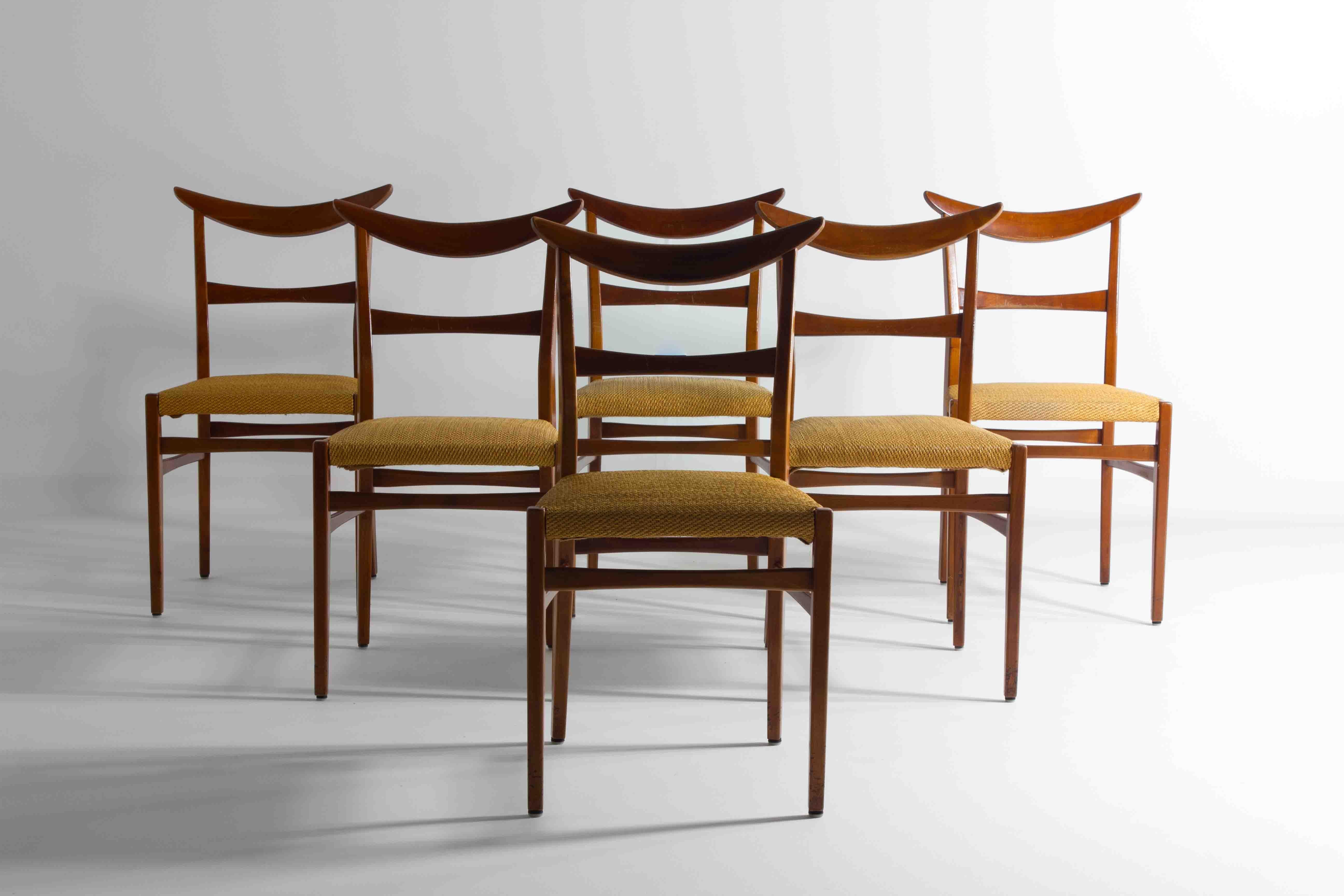 This mid-century set of six dining chairs exemplifies timeless design with its teak wood construction and unique arched backs. Each chair boasts a rich, warm hue that highlights the natural grain of the wood, ensuring that they bring a touch of