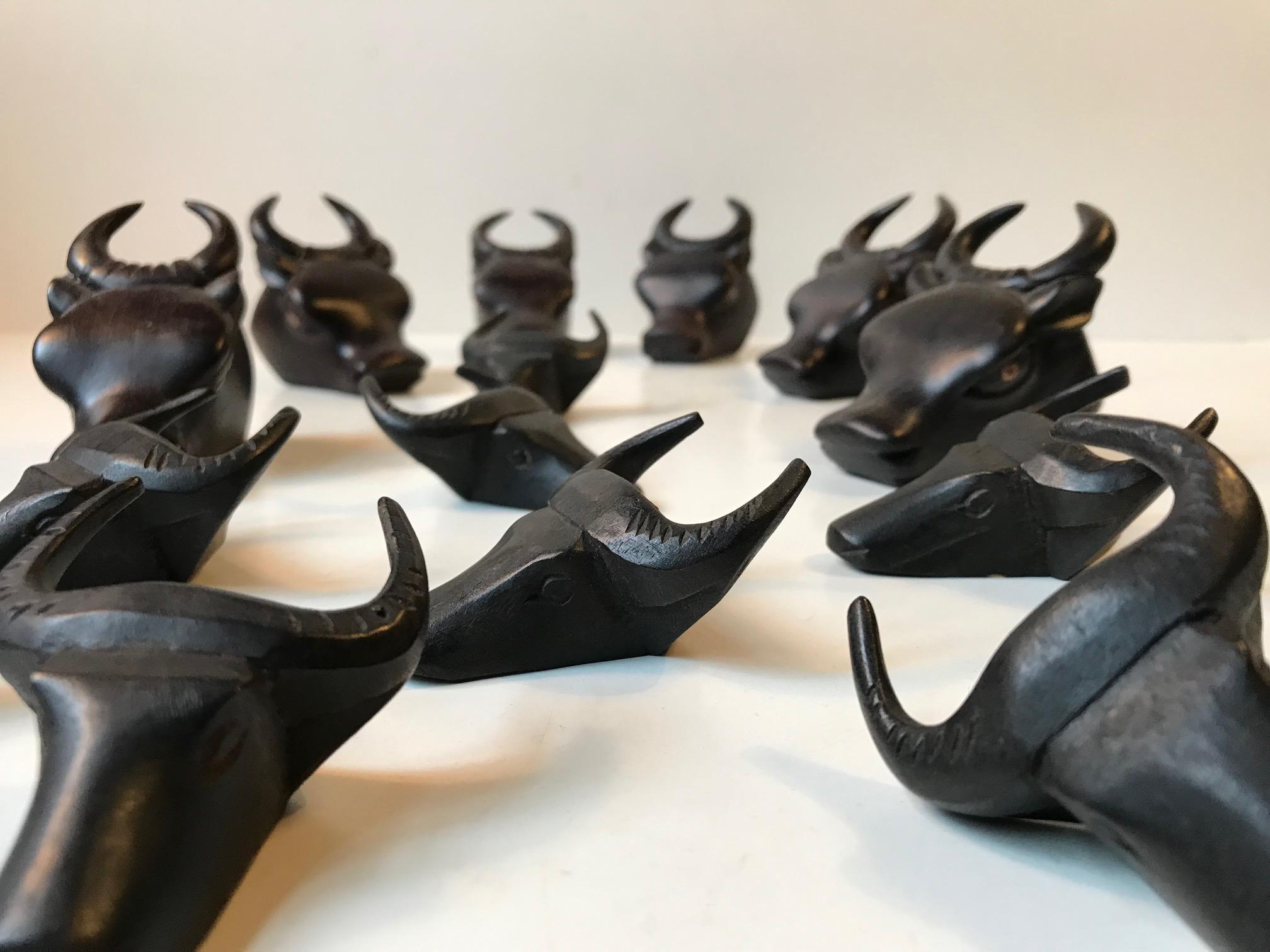 Unusual set of napkin rings hand carved in ebonized wood. There are 6 of the large version with fine detailing and colored eyes. The 8 small ones are more crudely made. This lot was made in Spain during the 1960s or 1970s by a local artisan. For