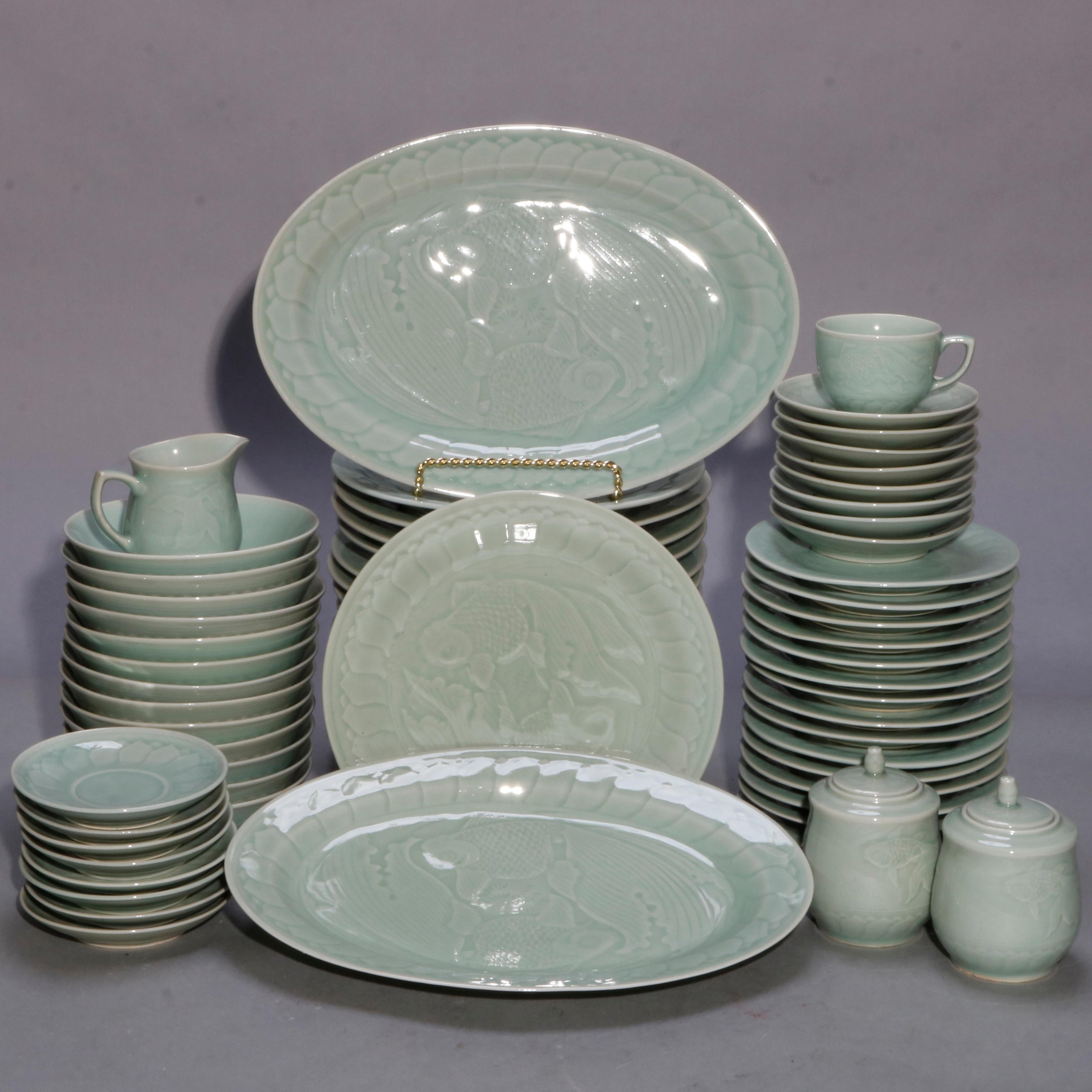 A vintage set of Chinese dinnerware offers porcelain construction with celedon glazing and embossed koi fish decoration, stamped on back as photographed, 20th century; includes - 16 teacups/saucers, 2 platters, 16 plates, 2 creamers, 16 butter