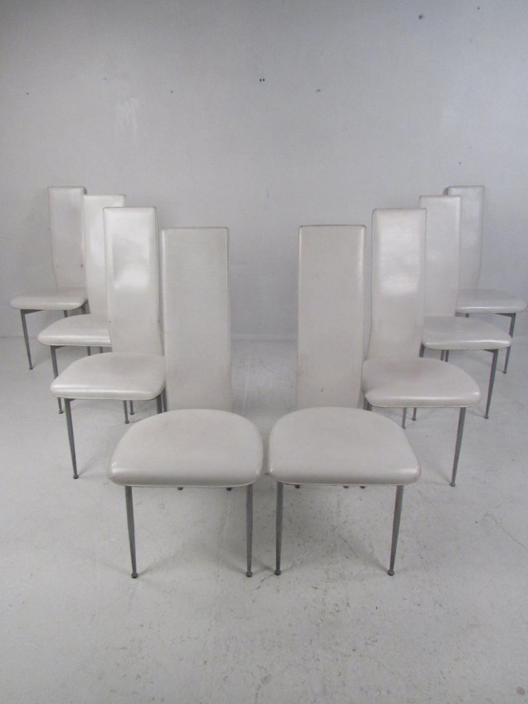 An elegant set of eight Mid-Century Modern high back dining chairs that have an unusual metal base. The sleek design ensures maximum comfort with its high backrest and thick cushioned seat. The wild drumstick shaped metal legs and convenient bend on