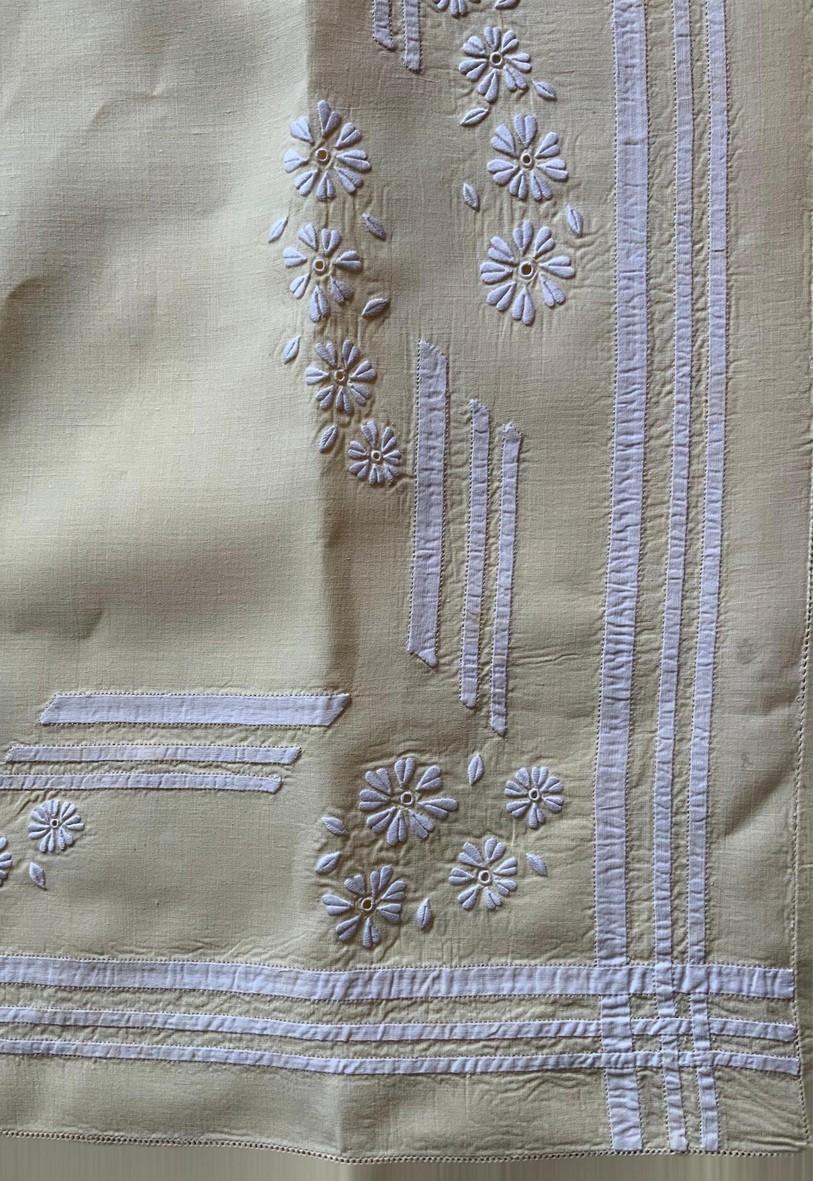 This is a vintage set of two bed linen full/queen flat sheets and two pillowcases. They are light yellow color. One of them is embellished with some embroidered white Jasmine flowers and leaves. Delicate set of vertical white linen “ribbons” and