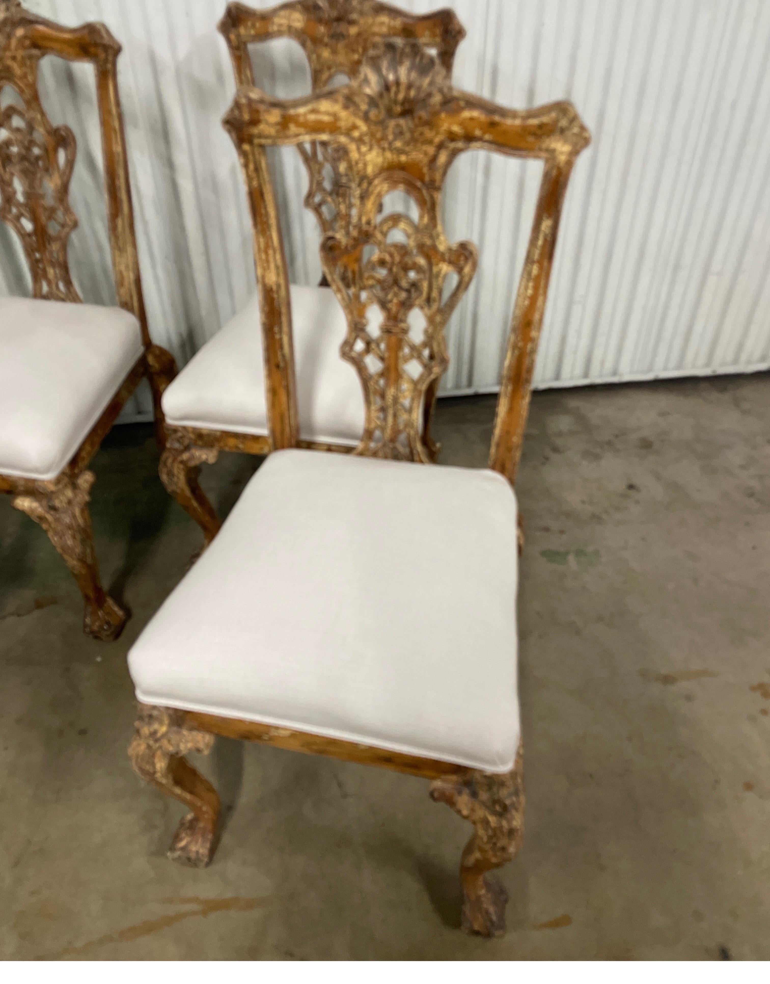 Beautiful set of four Chippendale style side chairs with a chippy painted finish. The chairs are nicely carved with a ball and claw foot. The back has a carved shell at top. Newly upholstered linen seat cushions.
