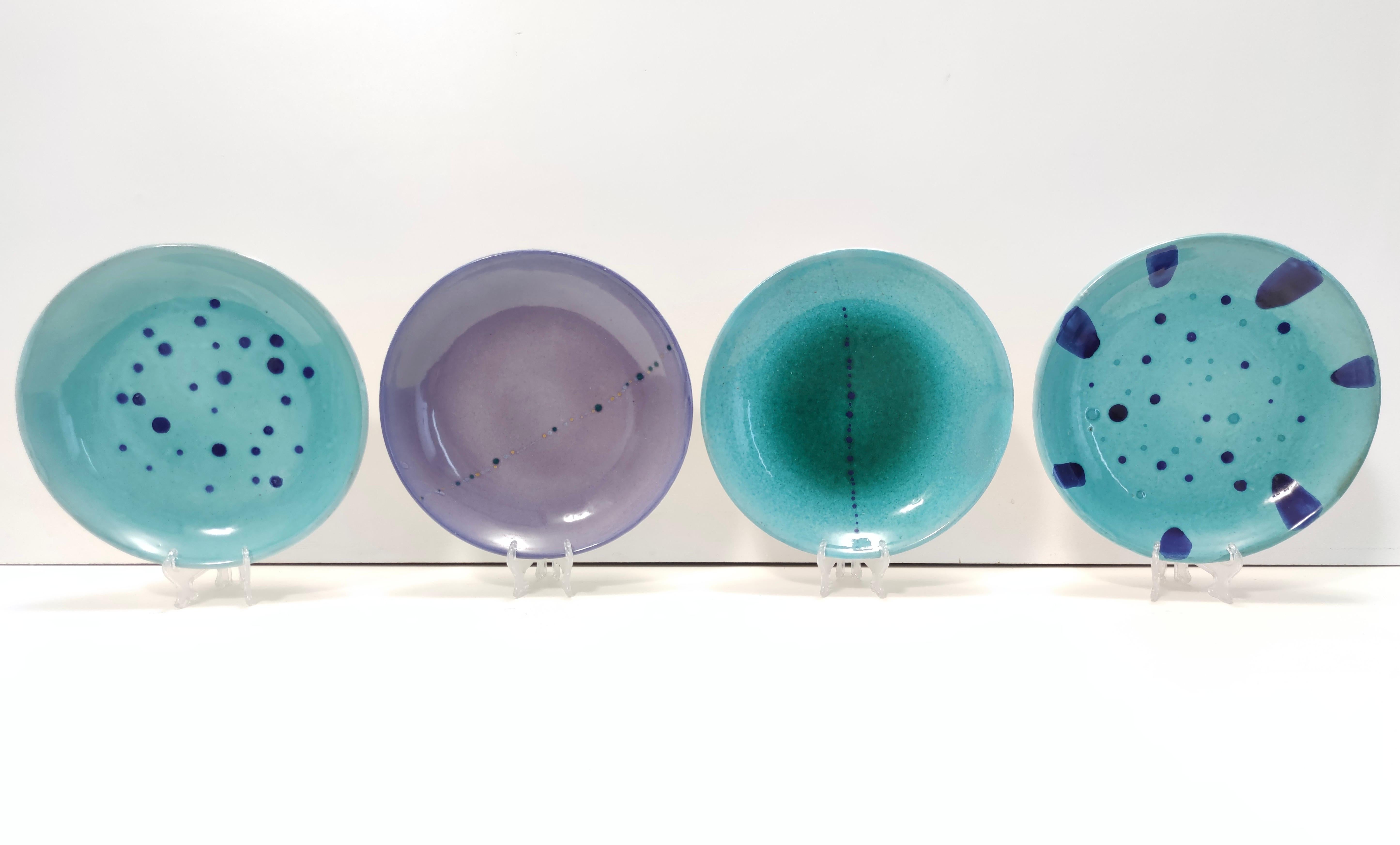 Made in Italy, 1950s - 1960s.  
This set of four catchalls / vide-poches / decorative plates is made in glazed earthenware.
These space-inspired plates are hand-made and hand-painted in the furnace of 