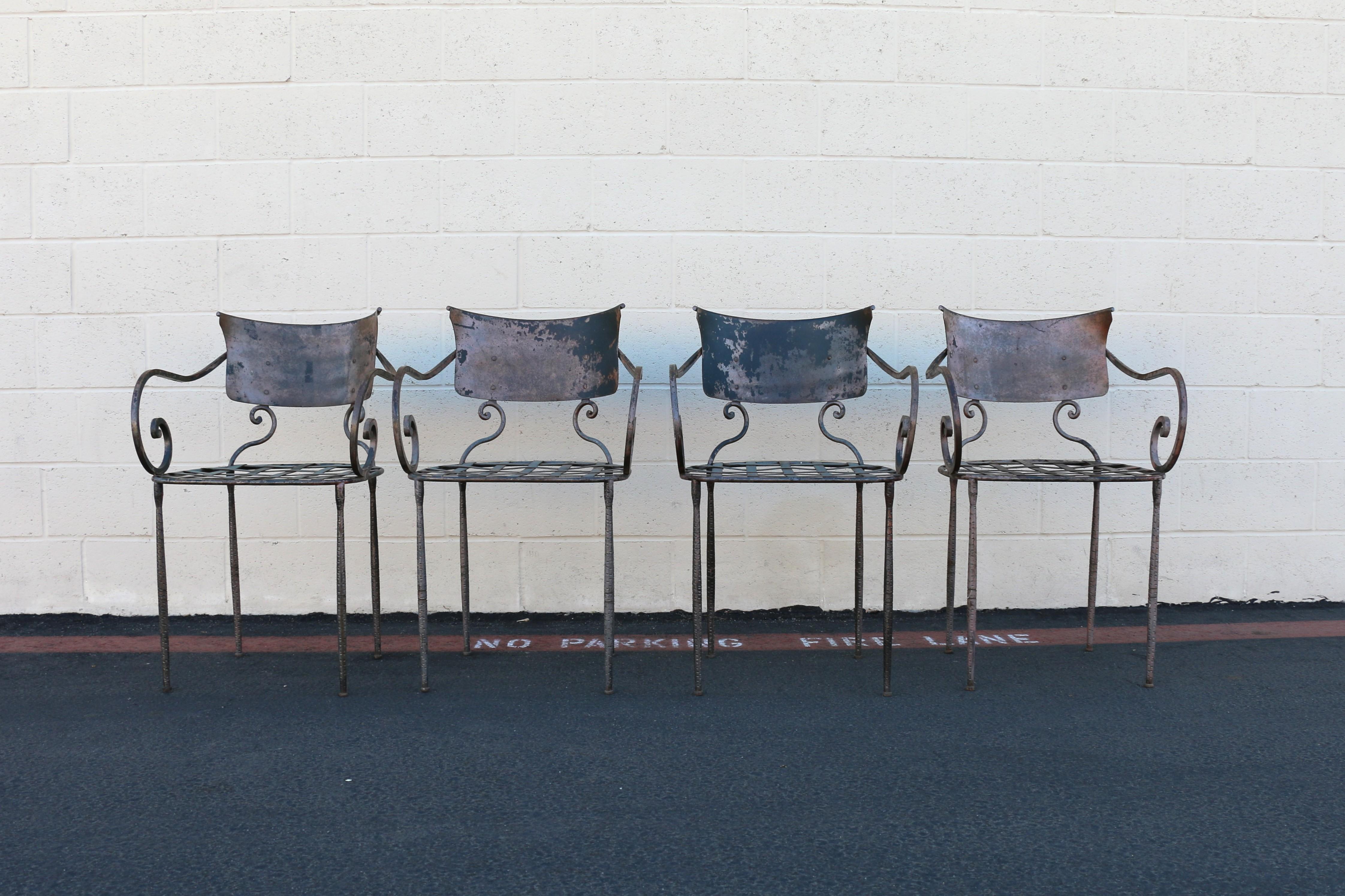 Spectacular set of four vintage metal wrought iron chairs, with a distinctive design. These wrought iron garden chairs, are featuring a classic design with curved backs and splayed legs. They exhibit an aged patina, and used outdoors signs. These