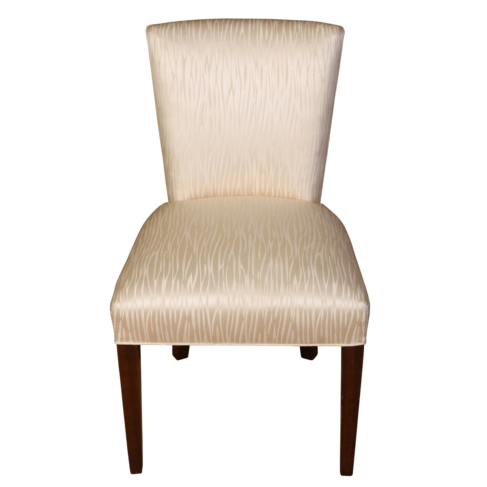 A set of four vintage upholstered dining chairs or games table chairs, modern style with ivory fabric, shaped back and narrow dark wood legs.