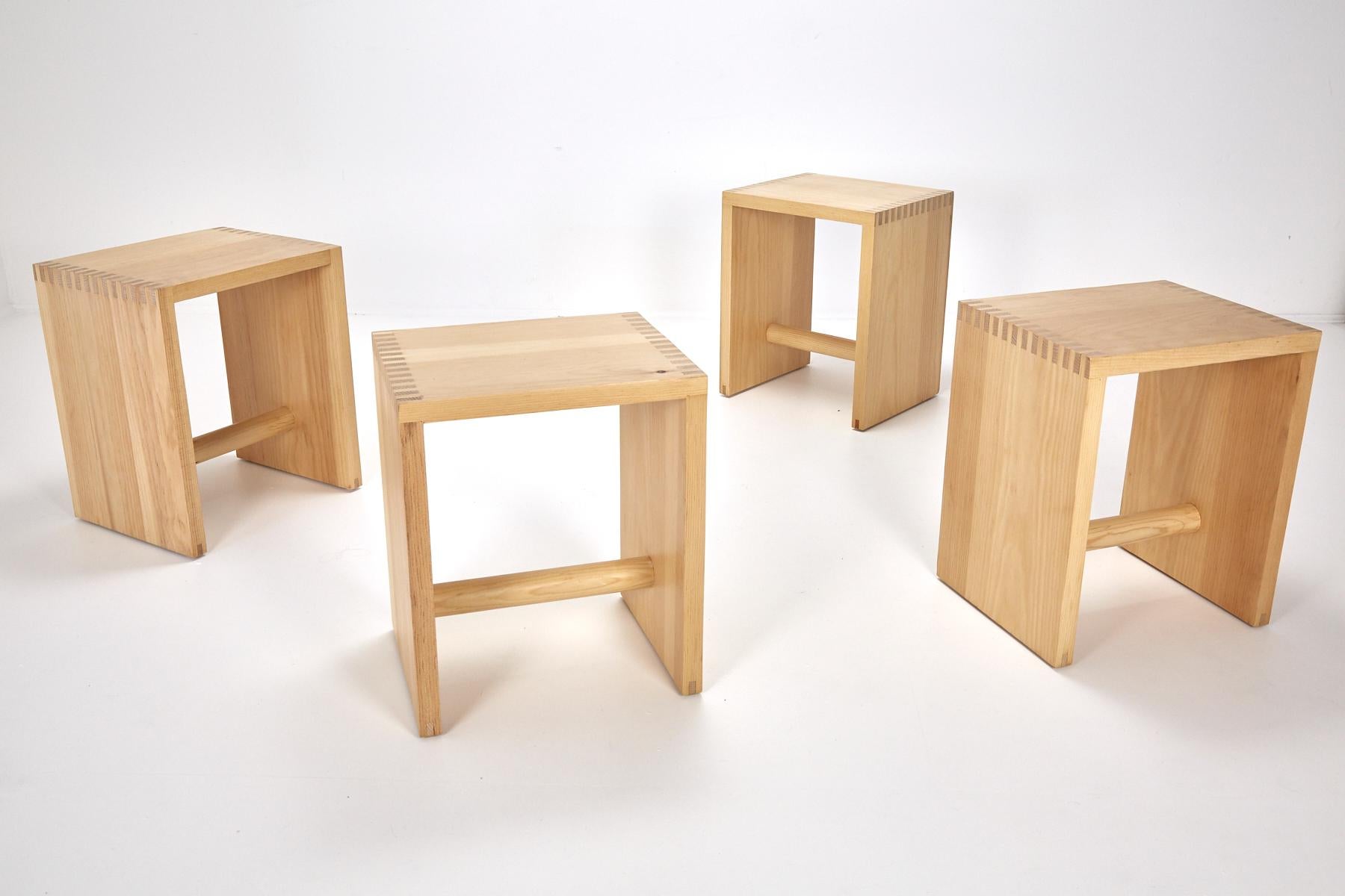 Set of four solid pine rectilinear stools with cylindrical foot rail. Edges show alternating wood grain in construction.

This multifunctional piece of furniture can be used as a seat, stand, side table, serving tray, and box for transportation.