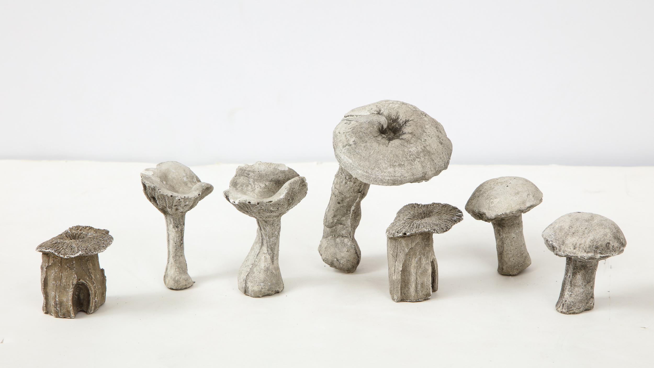 Set of seven small garden mushrooms on spikes for the garden, found in England. Made from molded concrete, they are each unique in size and shape. The tallest is four and a half inches tall and four inches wide. The smallest is two inches high and