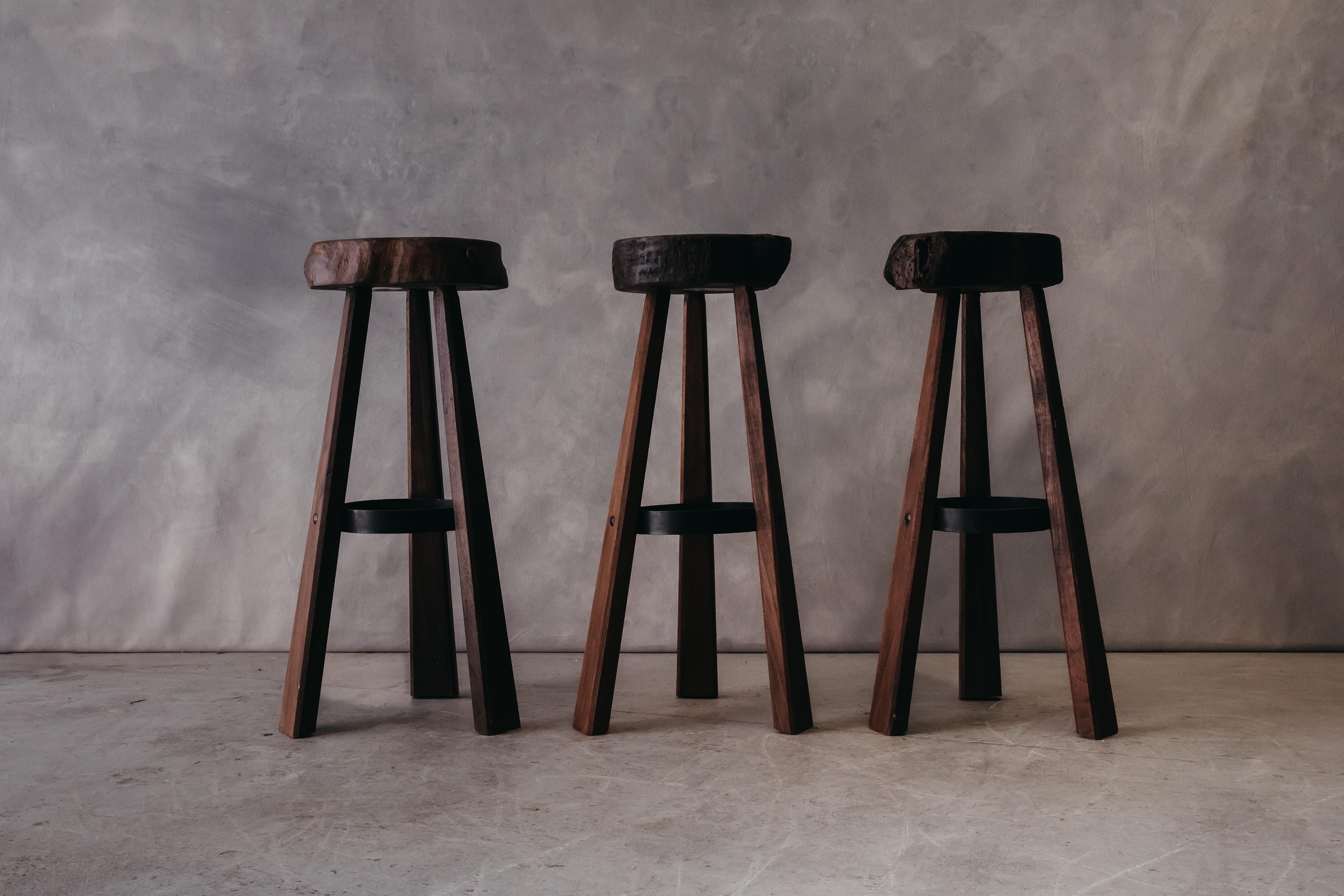 Vintage Set Of Three Brutalist Bar Stools From France, circa 1960. Live edge seats with a circular iron foot rest. Light wear and use.

We prefer to speak directly with our clients. So, If you have any questions or would like to know more please