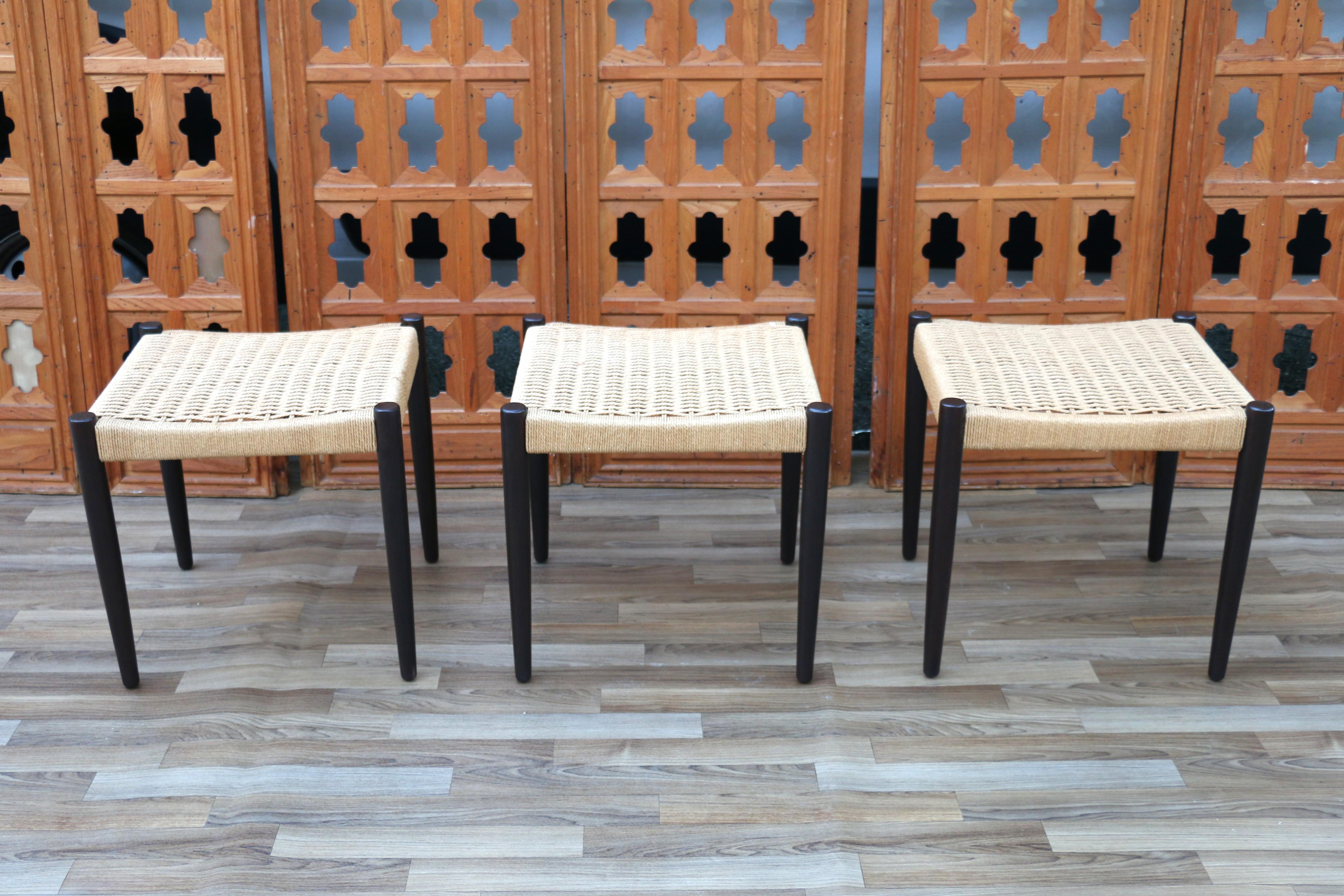 Icónico conjunto de tres taburetes daneses, sus patas son de teca y los asientos de cuerda de papel. Estos taburetes son originales de los años 50. El estado es absolutamente estupendo.  Taburetes muy robustos y fuertes. Absolutamente cómoda y de