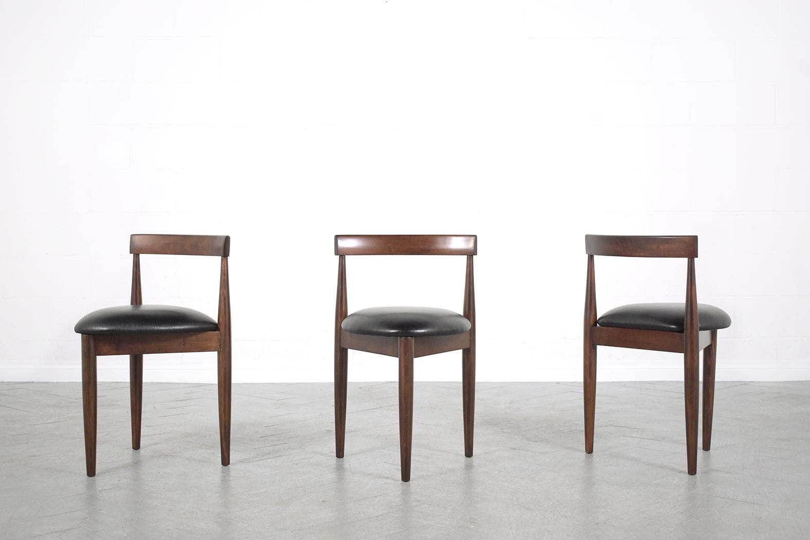 This extraordinary set of three Mid-Century Modern dining chairs in the manner of Hans Olsen executed in walnut wood and have been completely restored, refinished, and upholstered by our professional team of expert craftsmen. This fabulous set