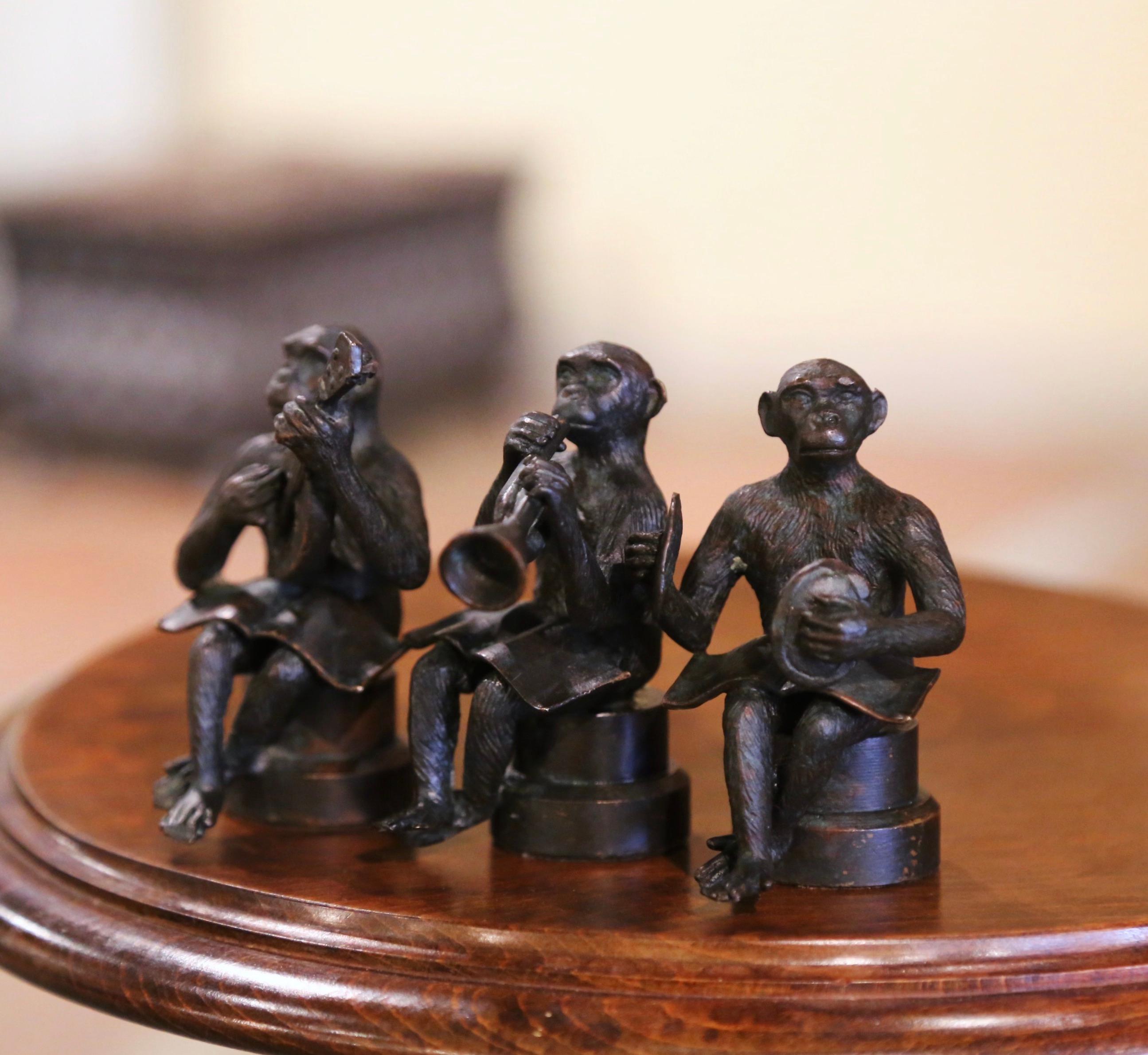 Decorate a library shelf or office with this set of antique miniature monkey sculptures. Created in France circa 1920, each Chimp is seated on a stool and playing an instrument with a music sheet spread across their laps; there is one monkey blowing