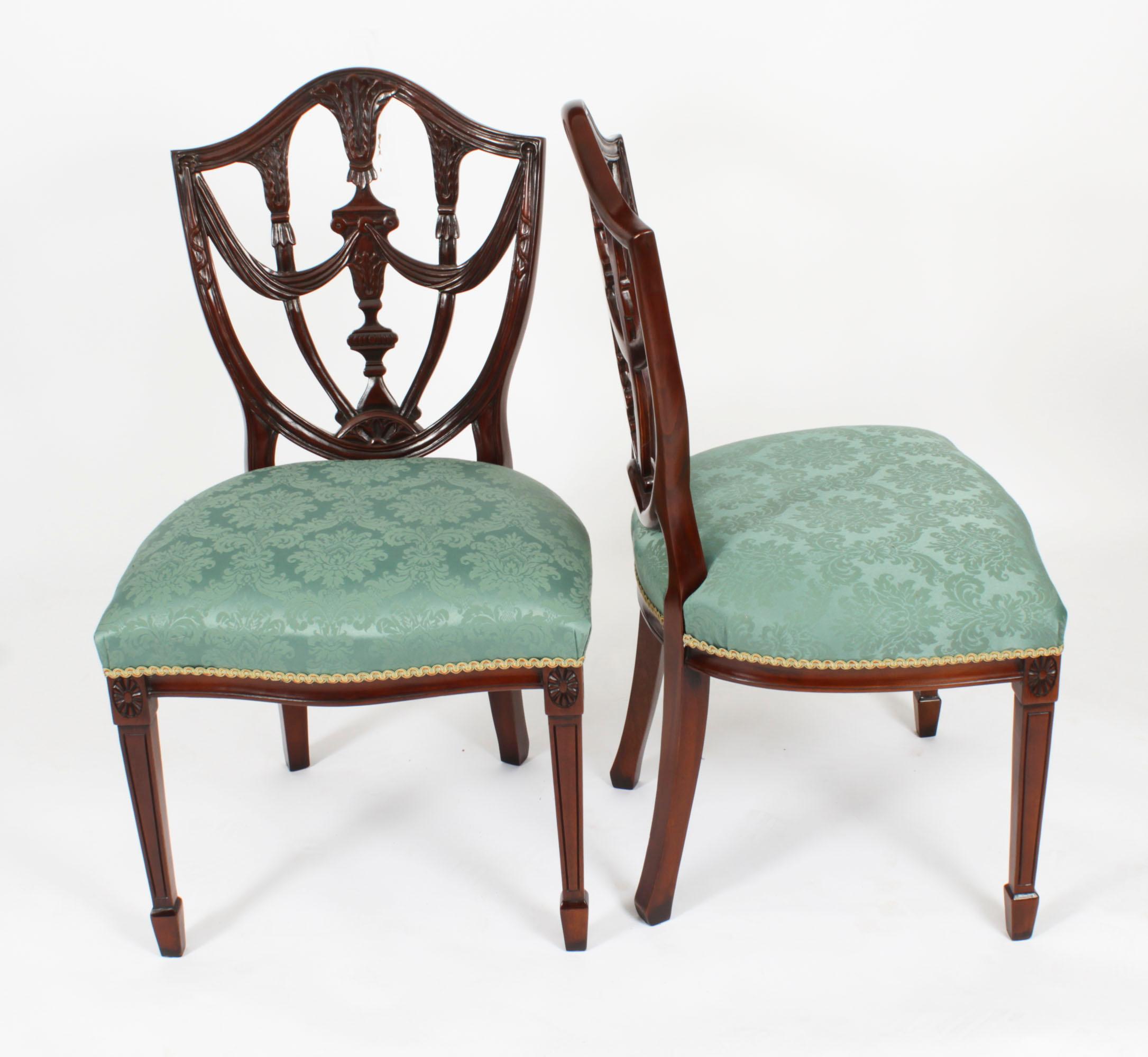This is an absolutely fantastic vintage set of twelve Federal Revival shield back dining chairs, dating from the second half of the 20th century.

These chairs have been masterfully crafted in beautiful solid mahogany with hand carved decoration