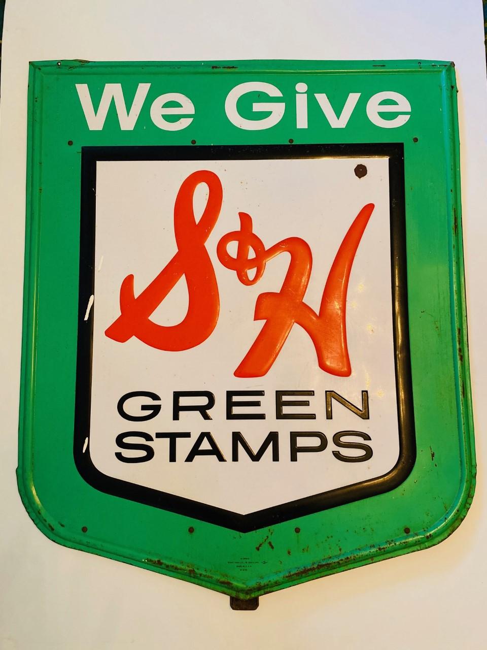 Vintage S&H Green Stamps sign that is colorful and large. The sign presents original colors of the advertisement in bright green, red and white with embossed lettering. The piece is 43” tall and 35” wide. The piece comes with backing ready to hand.