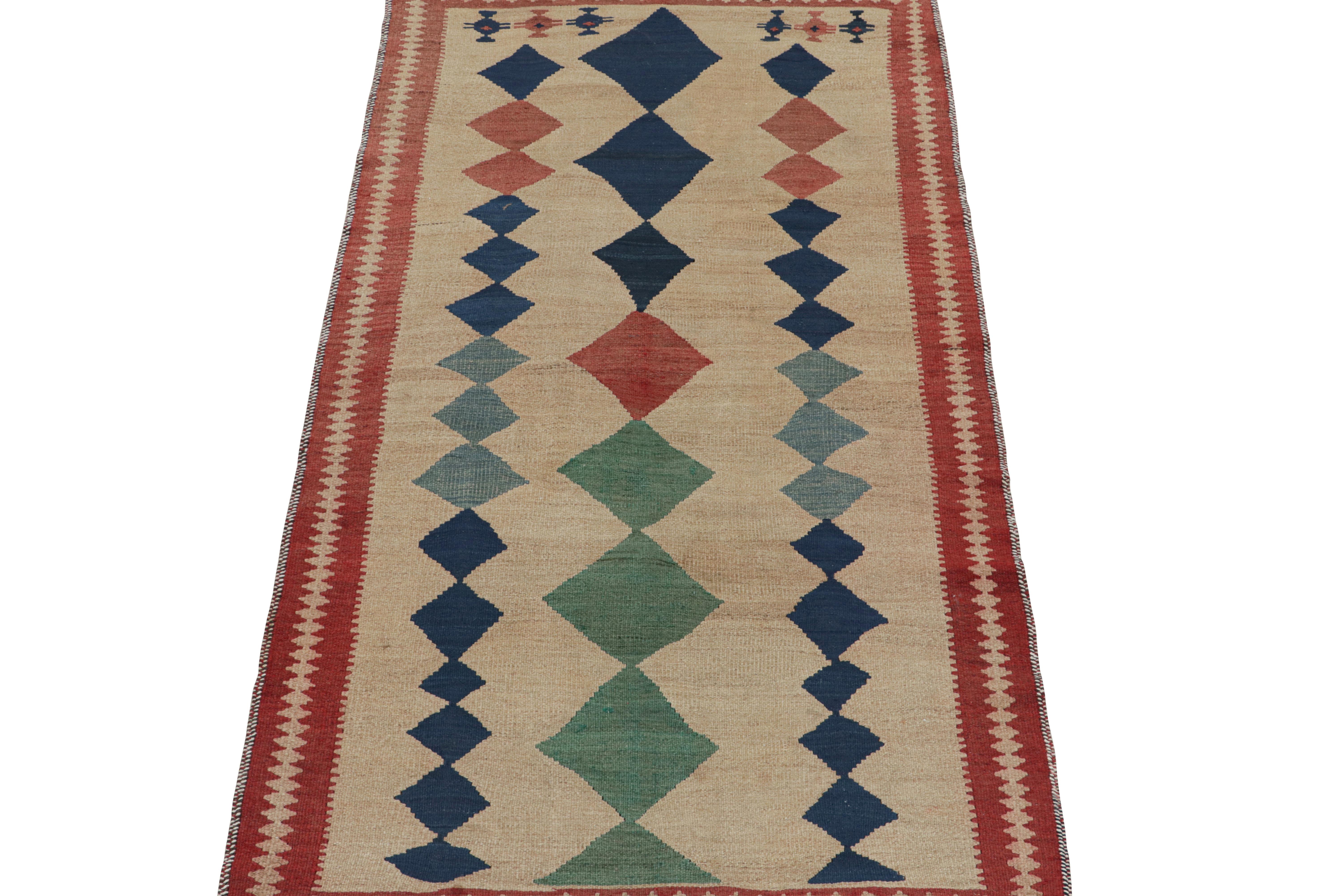This vintage 4x8 Persian kilim is believed to be a Shahsavan tribal rug.

Handwoven in wool circa 1950-1960, its design favors a beige field with red, navy blue and teal diamond patterns. Keen eyes may further admire other motifs in the lower