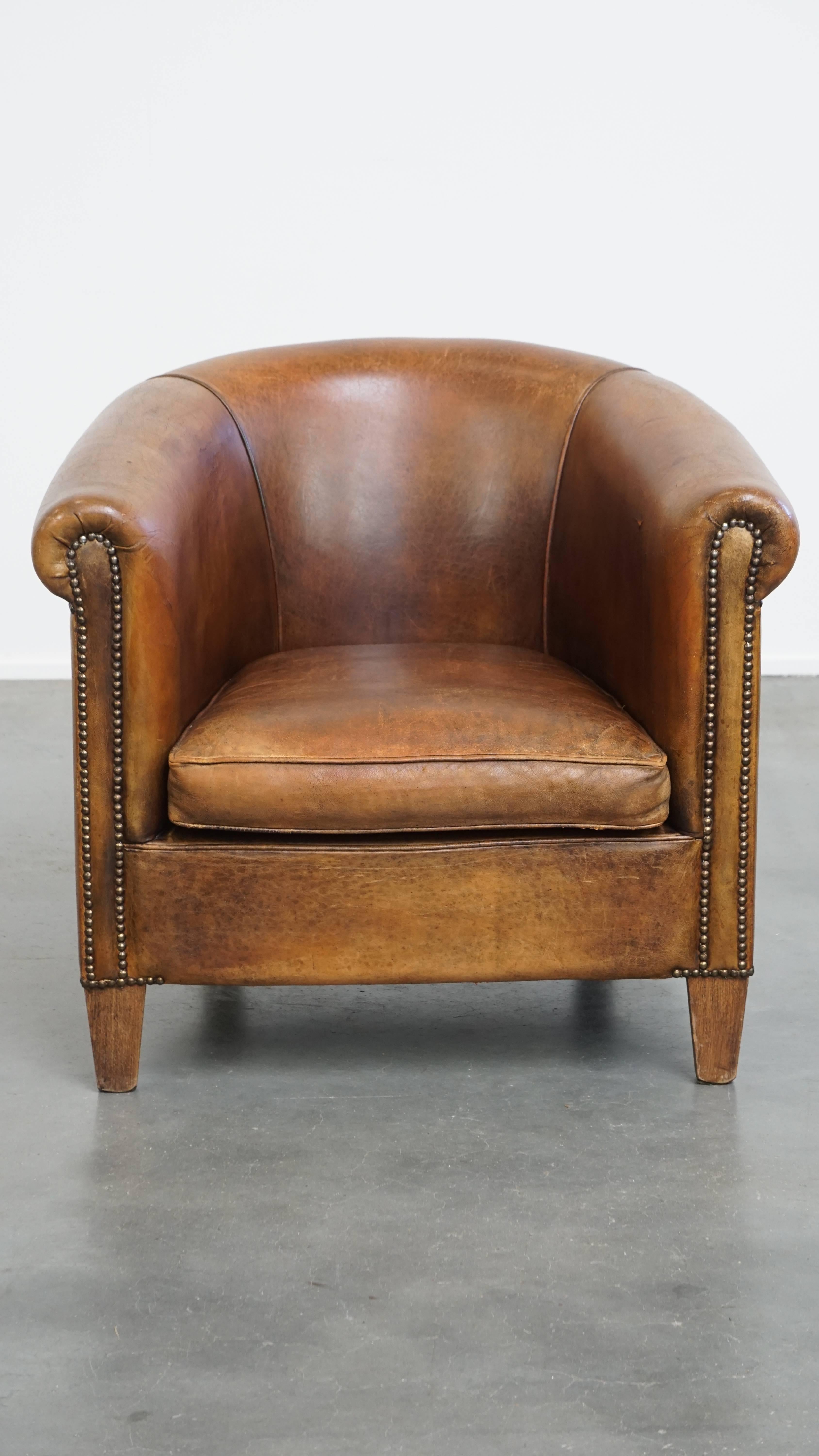Offered here is this characterful vintage club armchair made of sheepskin leather, finished with decorative nails and featuring beautiful colors. 

Over the years, this fantastic vintage sheepskin leather club chair has developed a wonderful patina