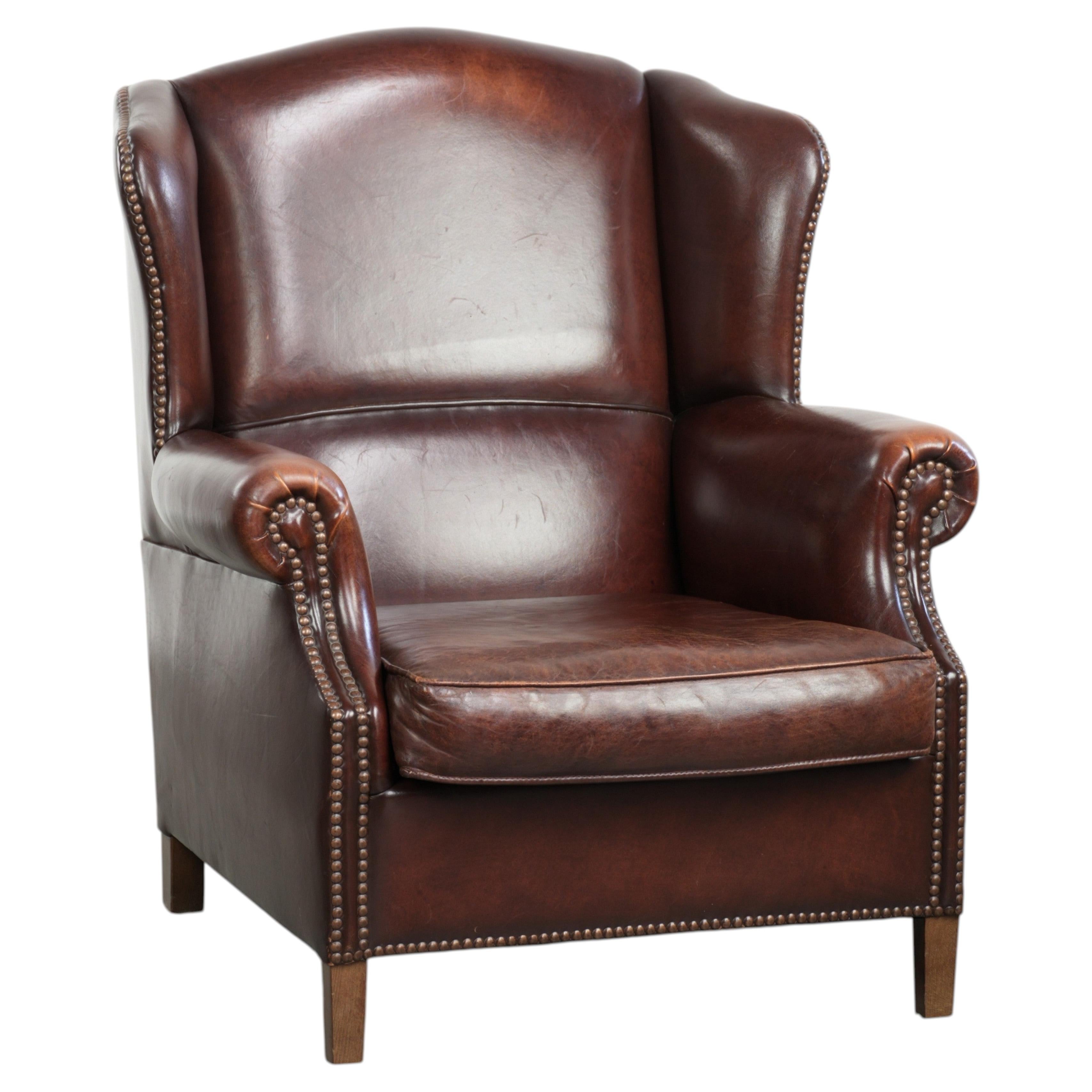 Vintage sheepskin wingback armchair with a timeless English look For Sale